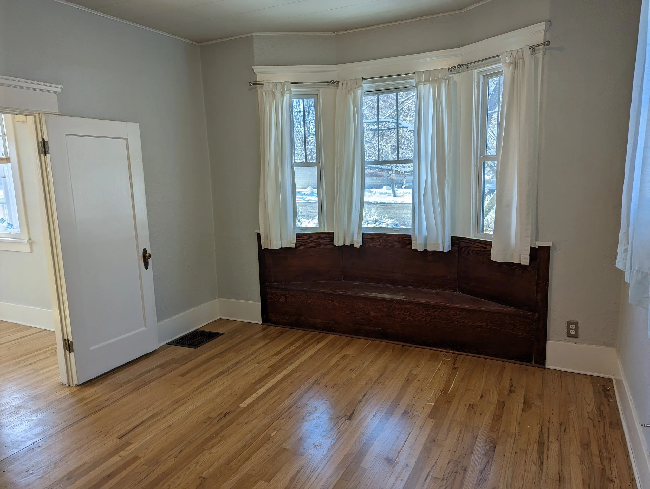 Modern bedroom remodel in Boise Idaho with built-in window bench seating and hardwood floors by custom home builder