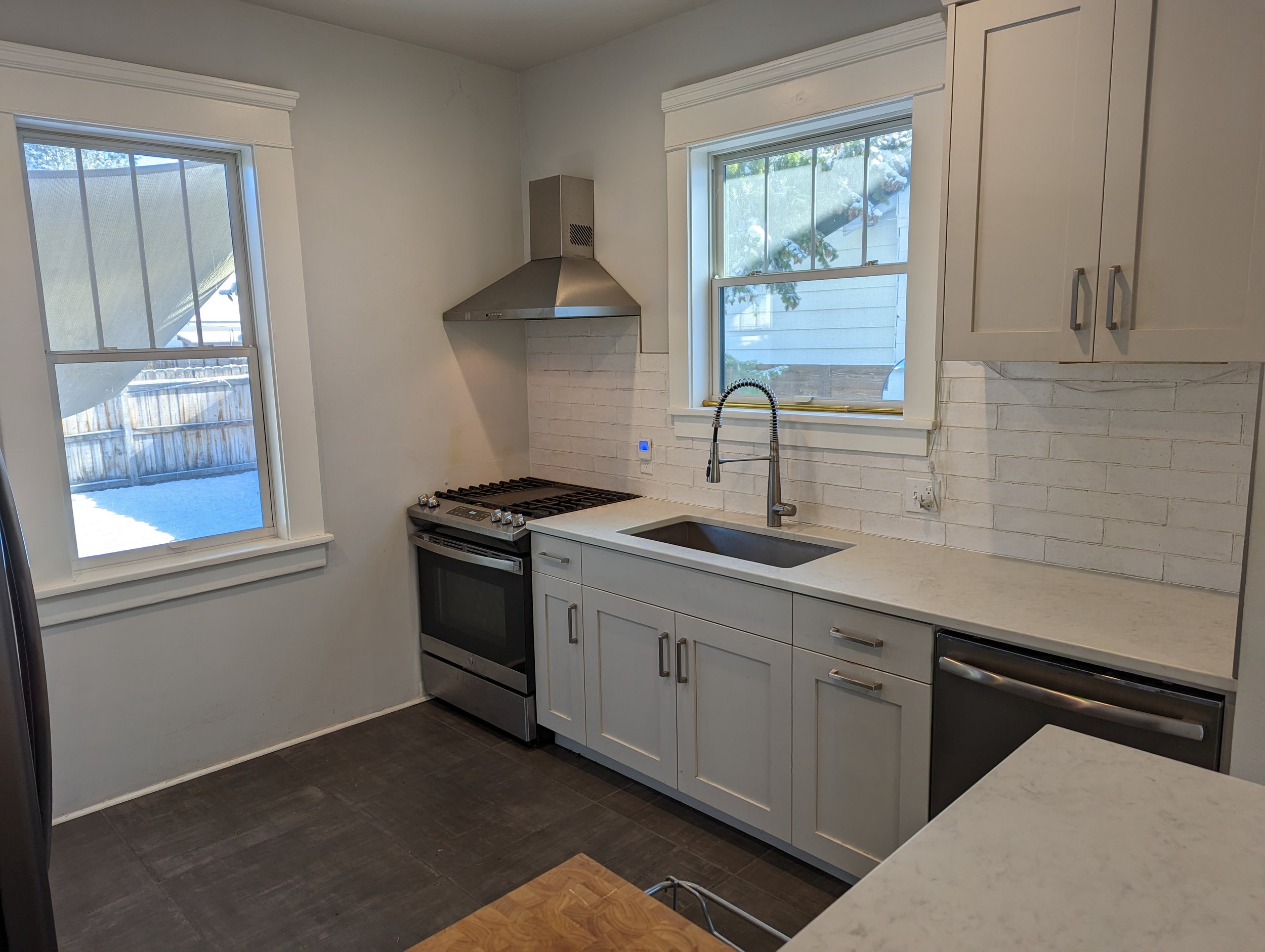 Modern kitchen remodel in Boise Idaho with custom cabinetry, quartz countertops, and tile backsplash by home builder