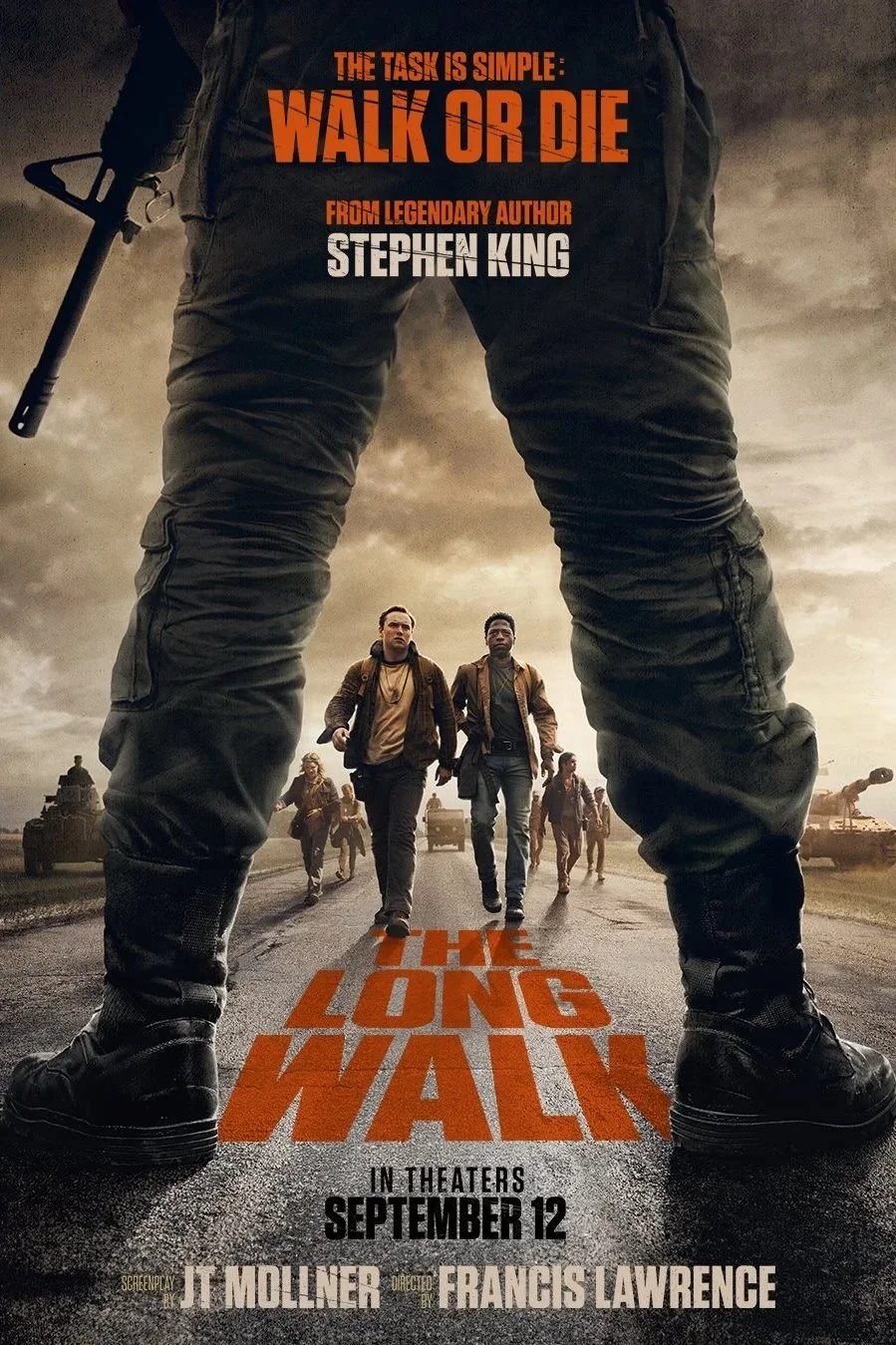 Poster for the movie "The Long Walk" featuring a person with legs apart in the foreground, holding a weapon, with a group of people walking down a road toward the viewer, tanks in the background, and stormy sky.