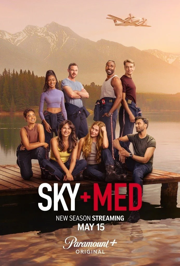 Poster for tv series Sky+Med featuring a group of seven diverse young adults posing on a wooden dock near a lake with mountains in the background, during sunset. An airplane is flying in the sky.