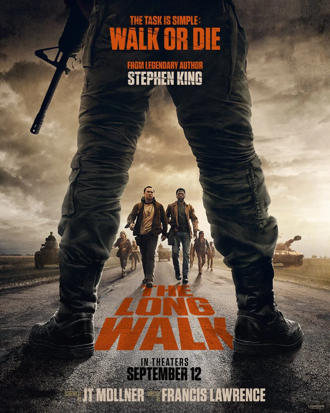 Movie poster for 'The Long Walk' featuring a large pair of legs with a rifle, a group of people walking on a road, and tanks in the background. The text highlights the tagline and release date.