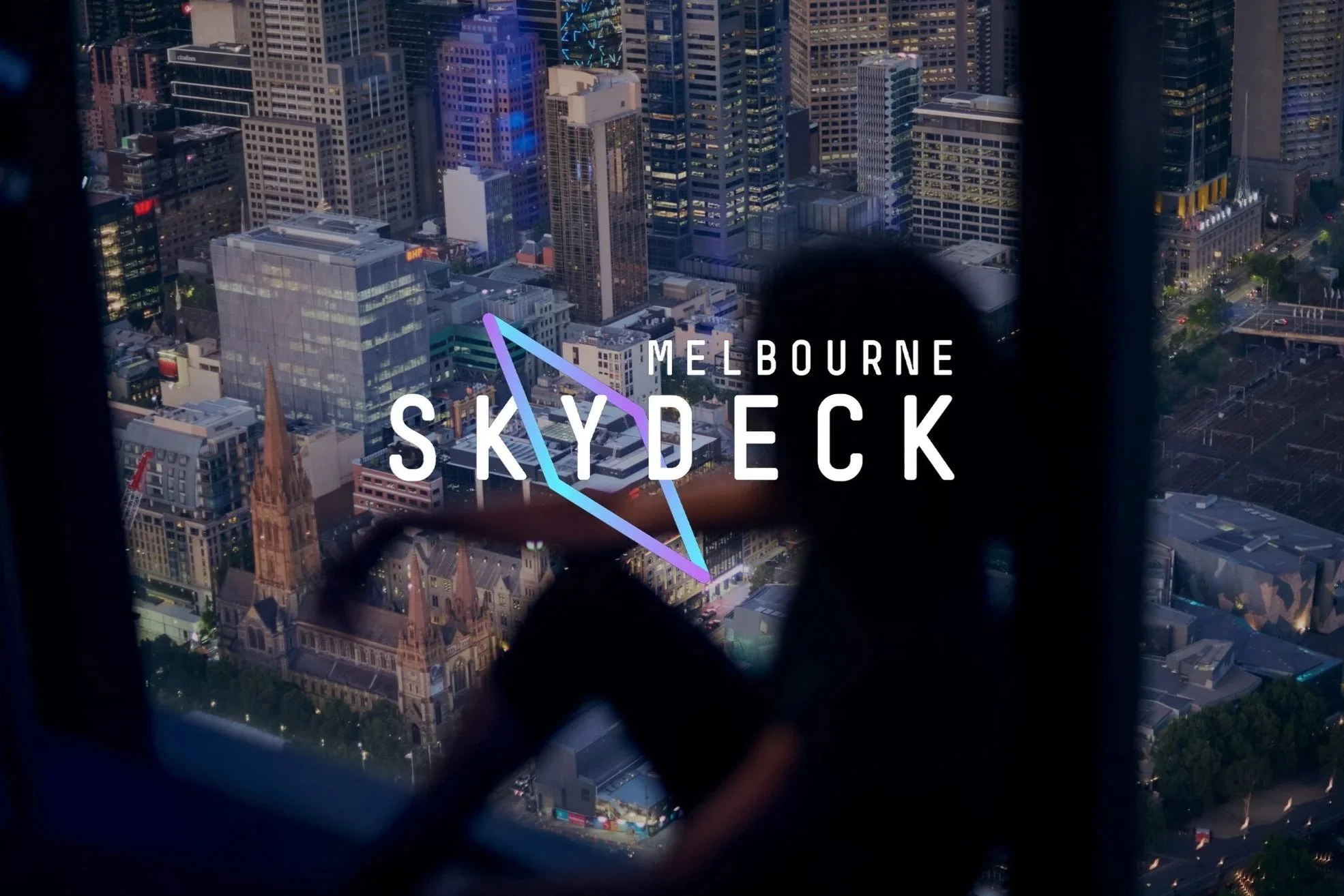 City skyline of Melbourne viewed from a high-rise window, with the logo of Melbourne Skydeck overlayed.