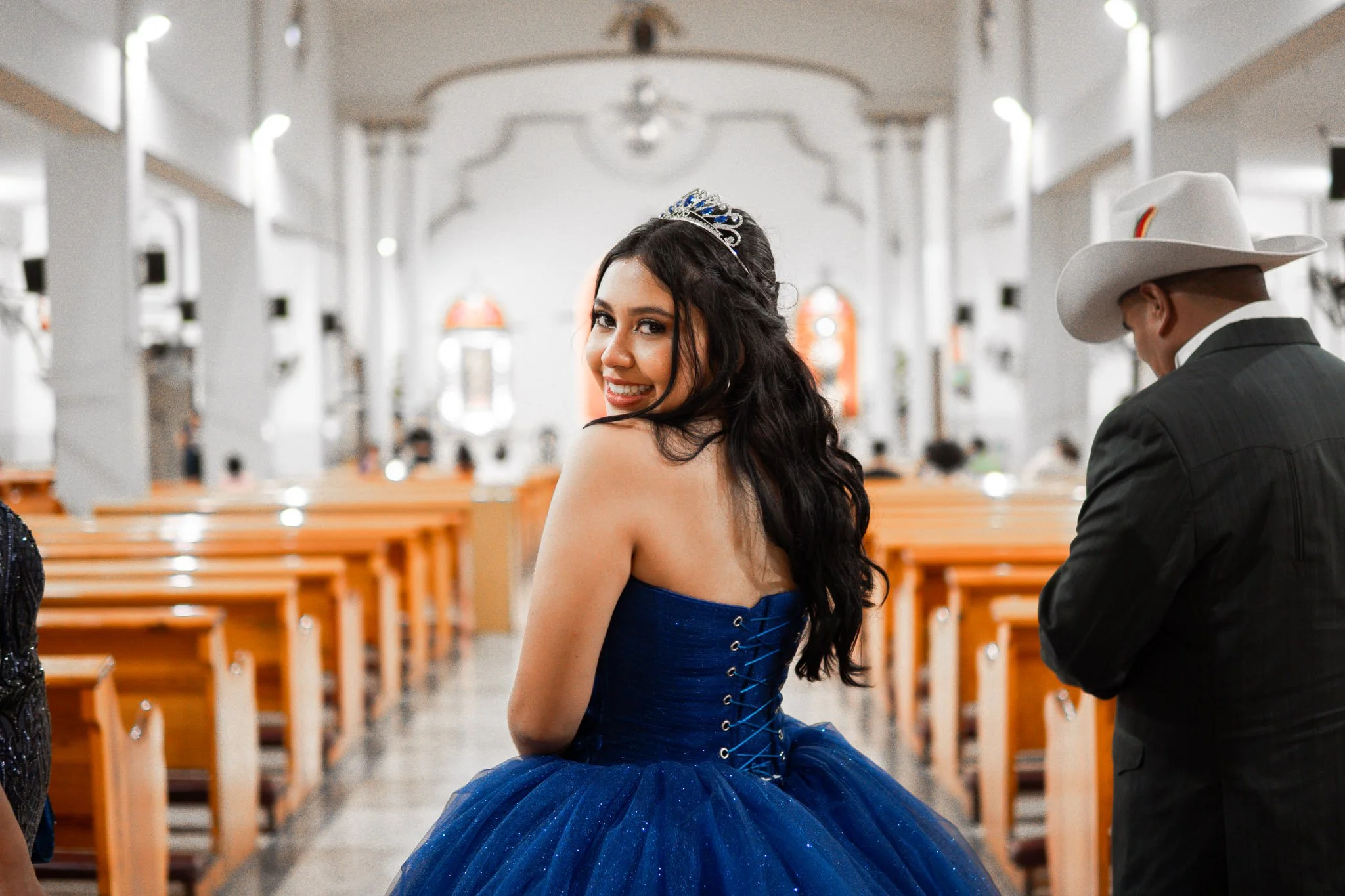 Jovencita con vestido azul, diadema y cabello rizado, sonriendo en iglesia