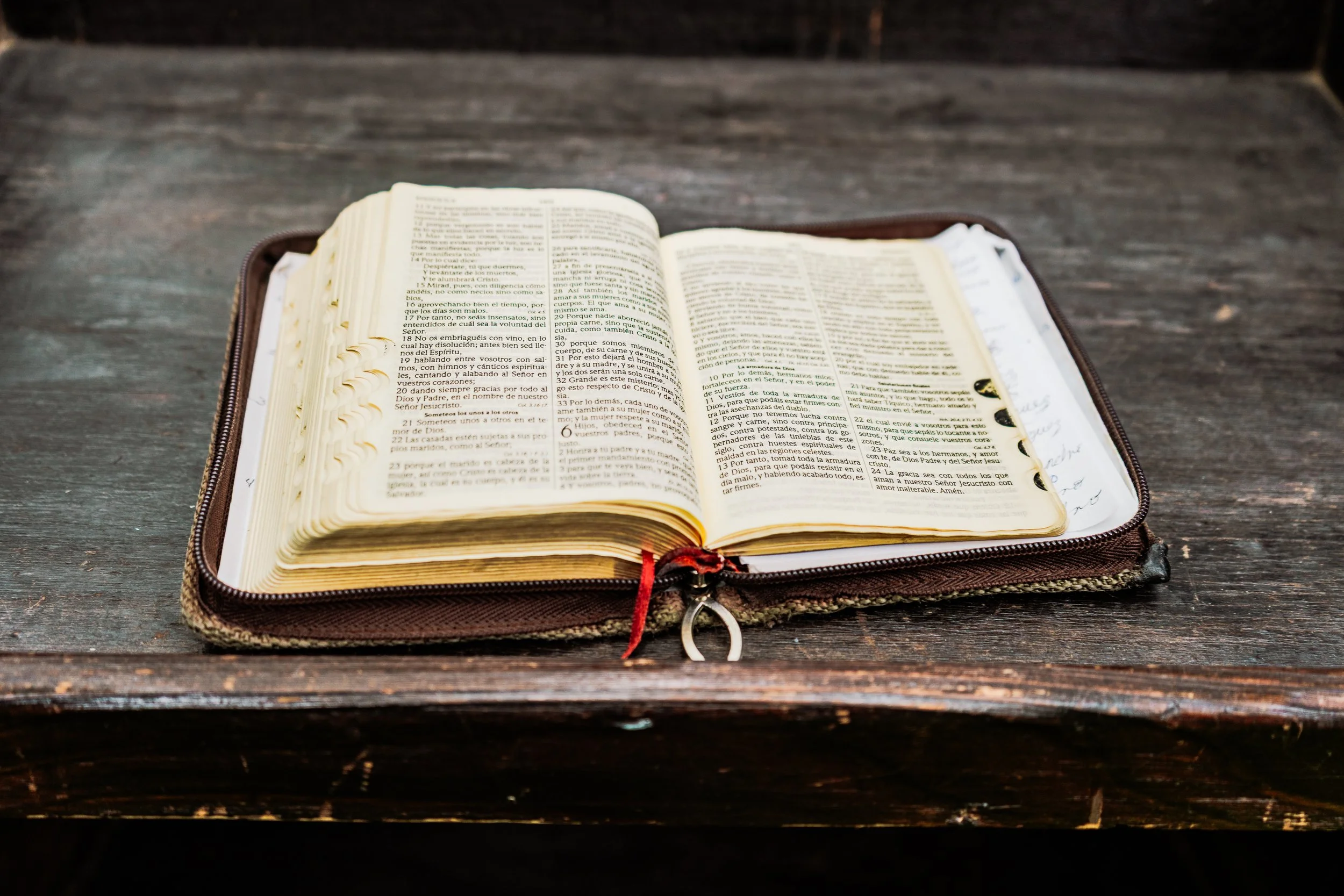 Biblia abierta sobre una mesa de madera oscura.