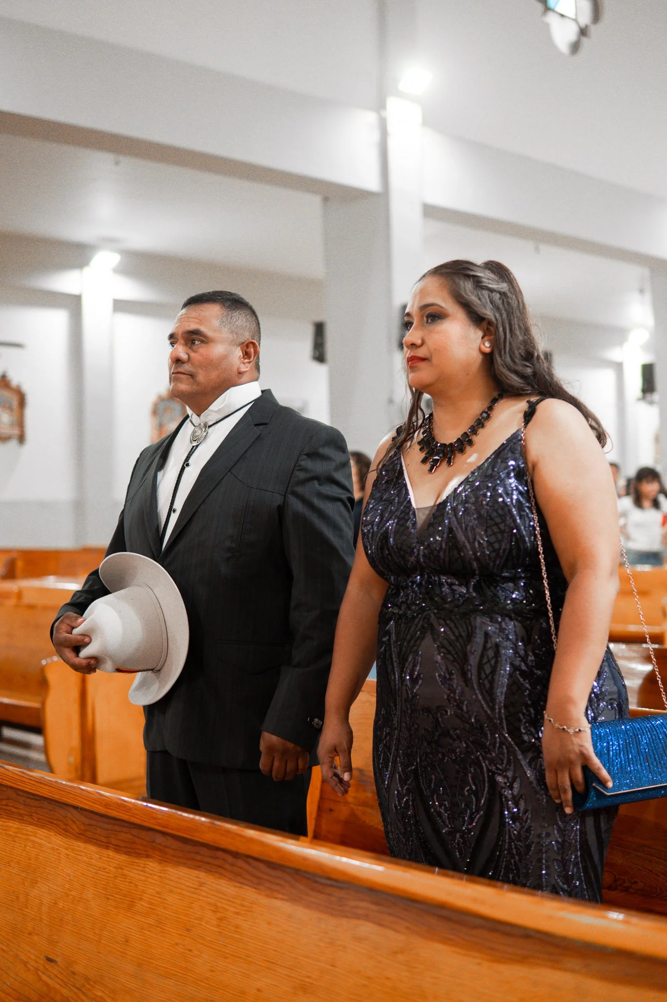 Hombre y mujer en una iglesia, vestidos formalmente, asistiendo a una ceremonia
