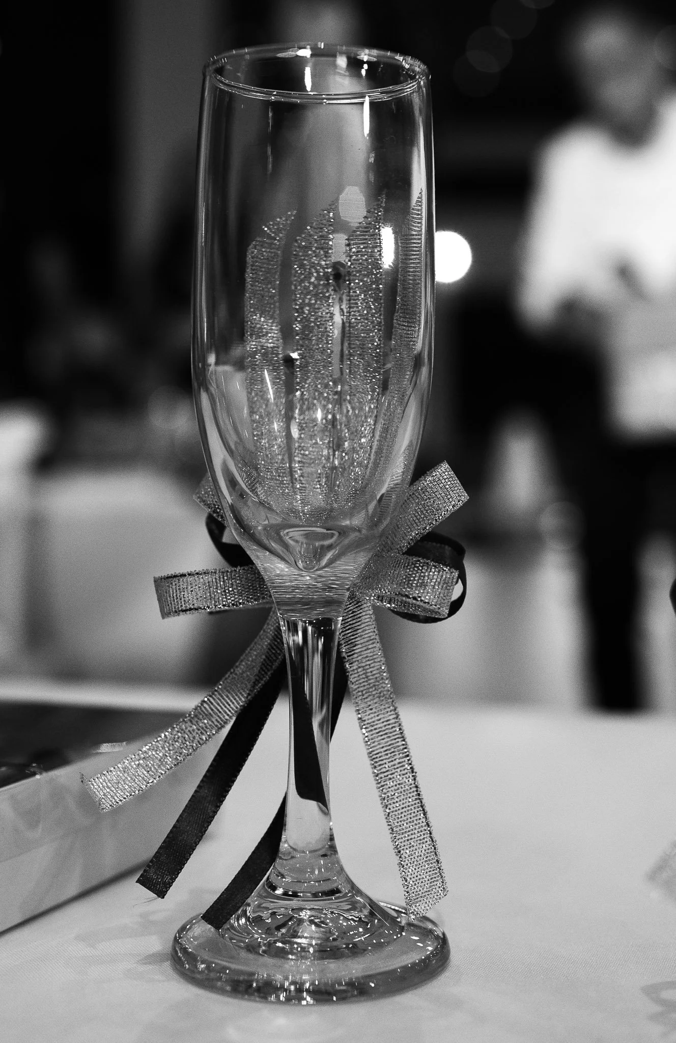 Una copa de champagne decorada con un lazo en un evento festivo.