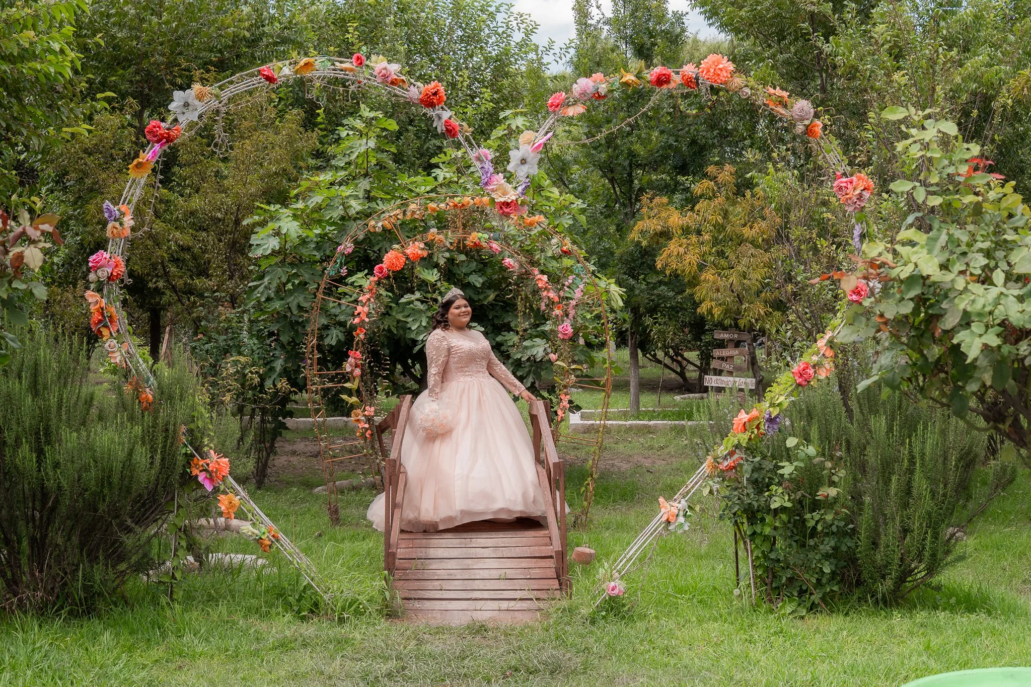 Joven vestida de rosa en un arco floral decorativo en un jardín