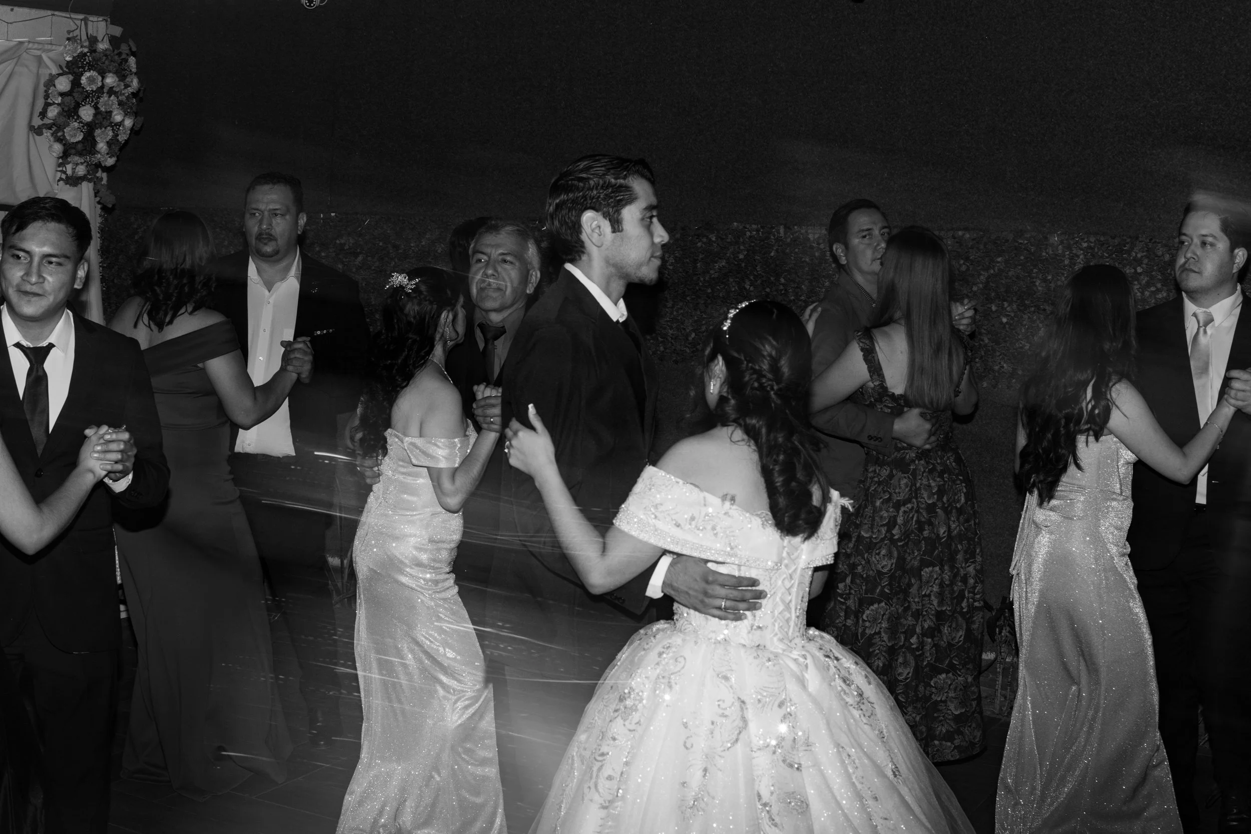 Personas bailando en una pista de baile en una ocasión especial, posiblemente una boda, en un entorno elegante y festivo.