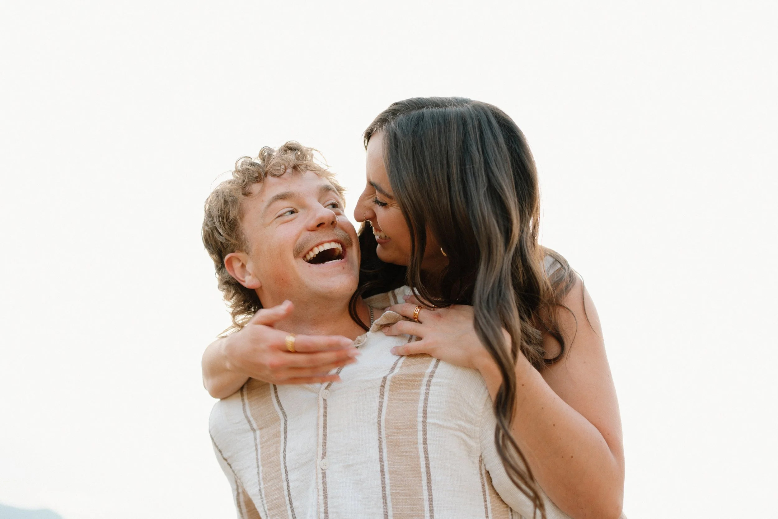 A happy couple sharing an embrace, with the woman smiling at the man, against a plain white background.