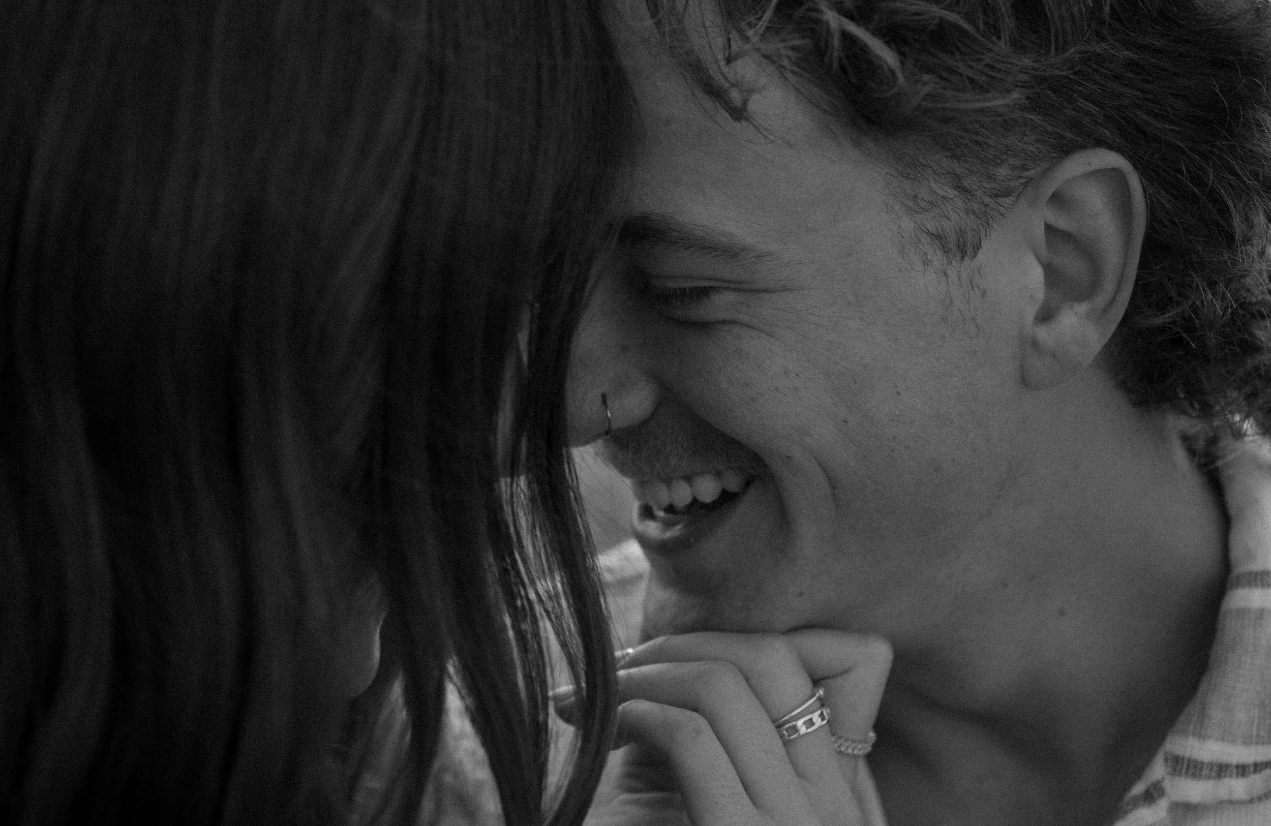 A close-up black-and-white photo of a happy couple with their foreheads touching, smiling, in a  couples photography session.