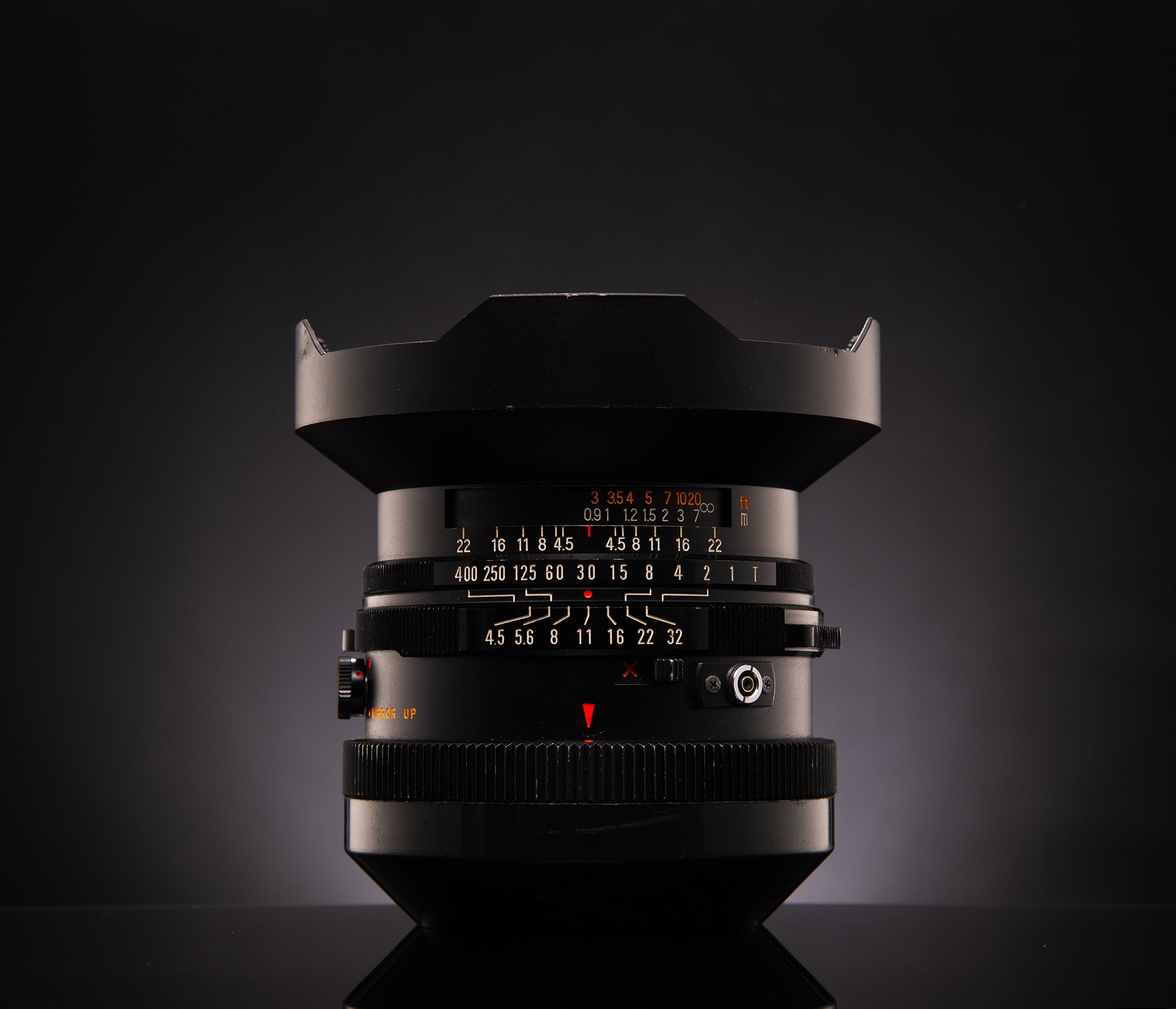 A professional camera lens with various adjustment rings, set against a dark gradient background.