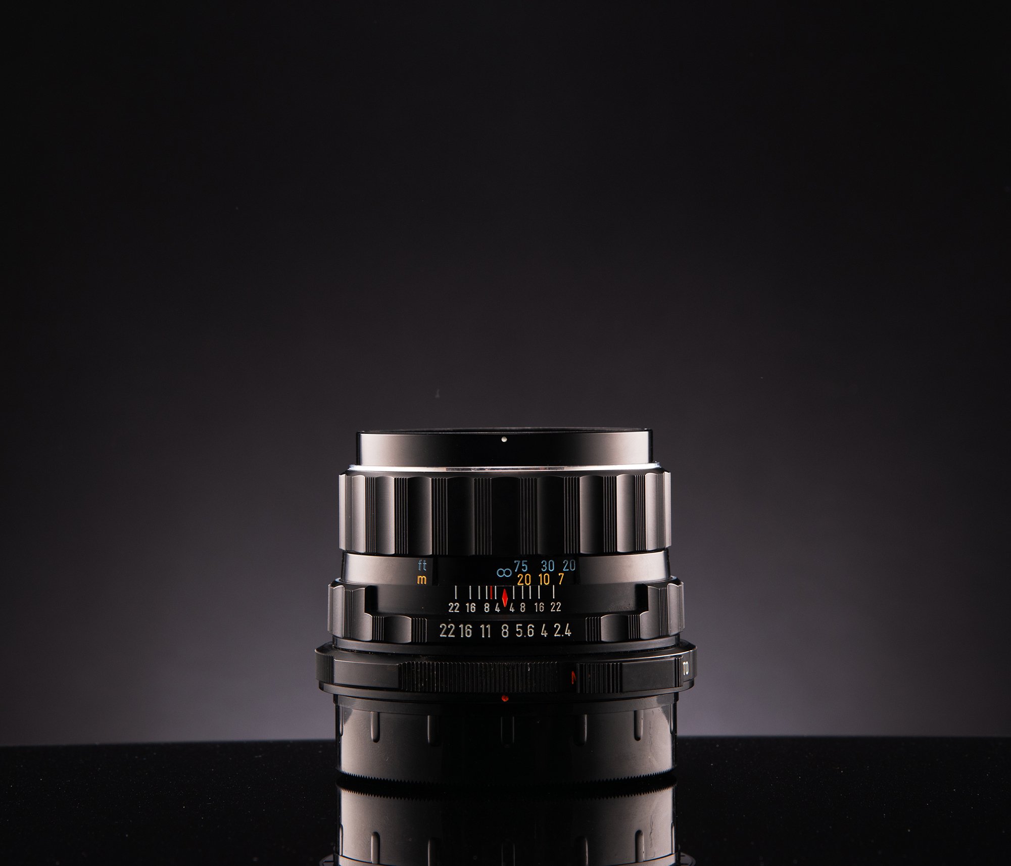 A camera lens on a black surface with a dark gradient background.
