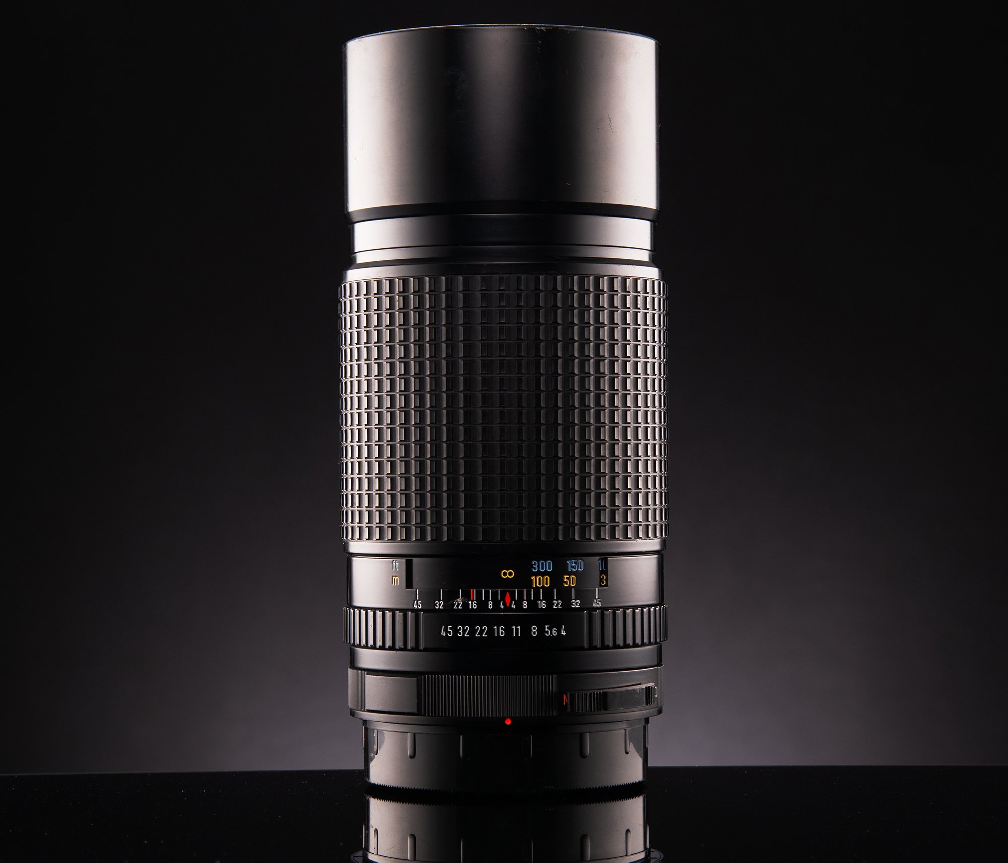Close-up of a vintage camera lens against a black background.