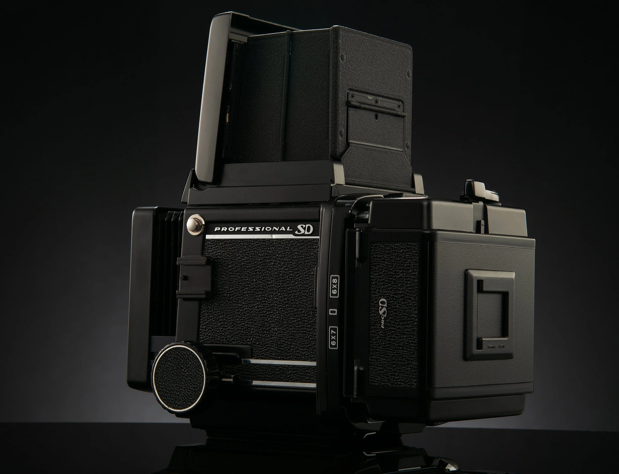 A black medium format camera with a waist-level viewfinder on top, labeled 'Professional SD,' against a dark background.