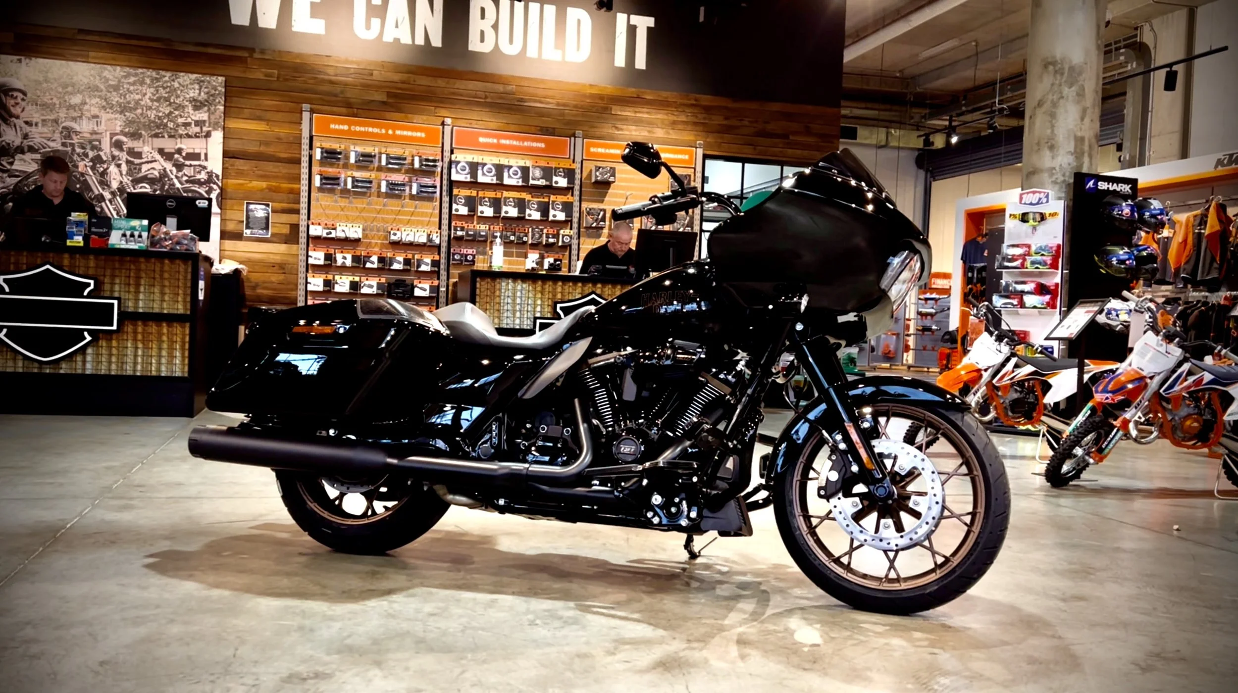A black Harley-Davidson motorcycle displayed inside a motorcycle shop, with other motorcycles and motorcycle accessories visible in the background.