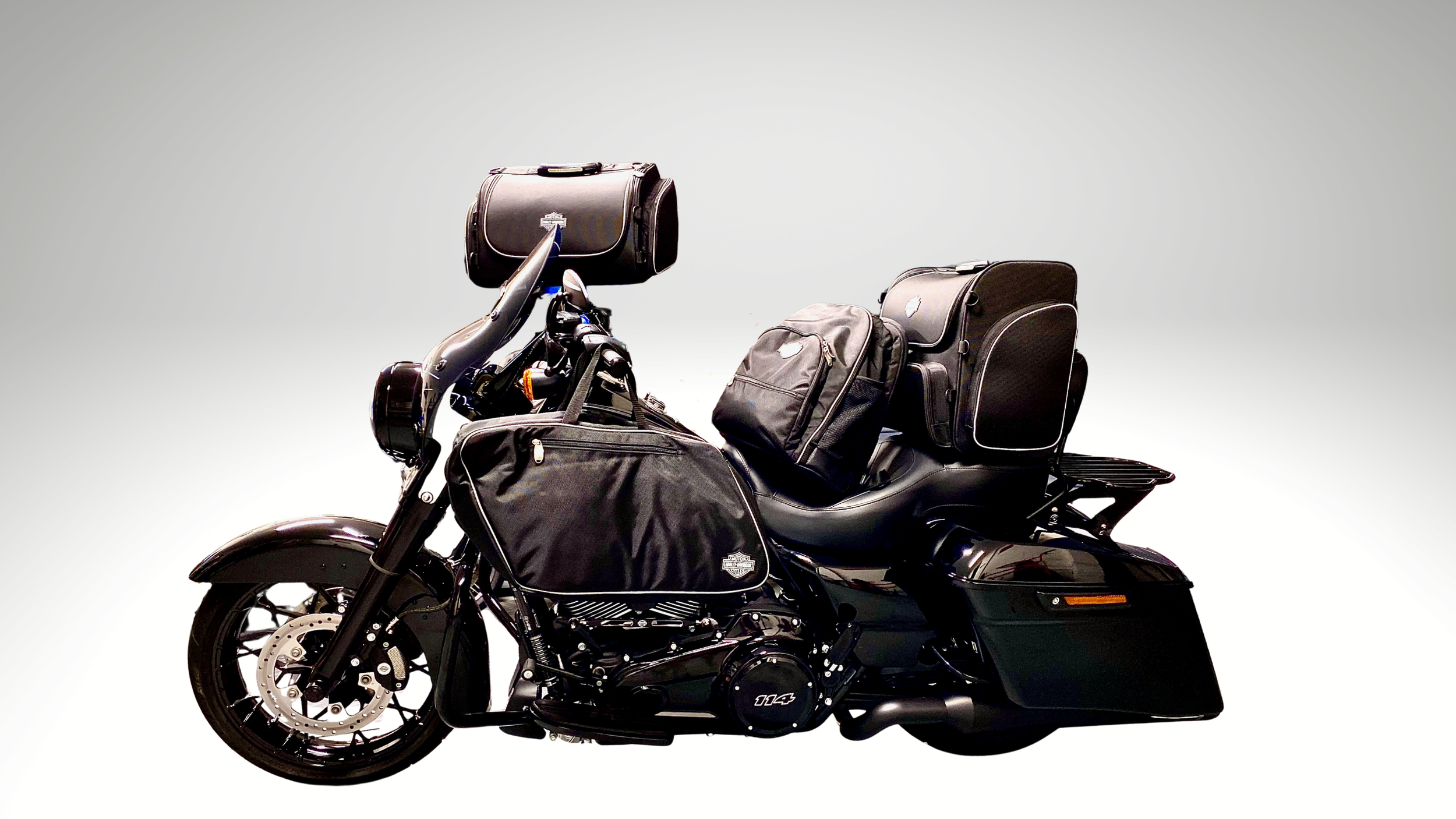 A black touring motorcycle loaded with multiple black and gray bags and luggage, set against a plain gray background.