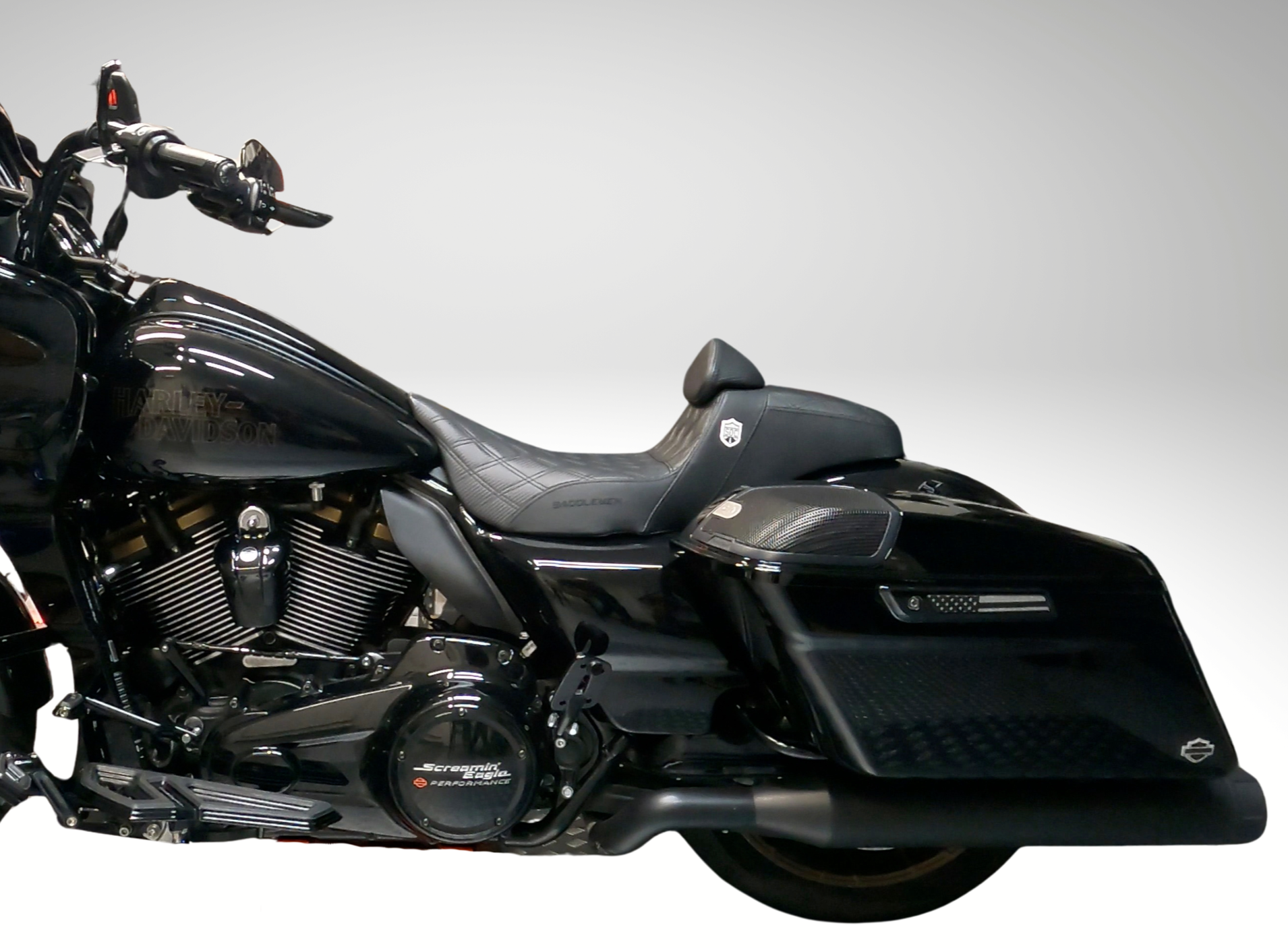 Black Harley Davidson motorcycle with a side saddlebag against a plain light gray background.