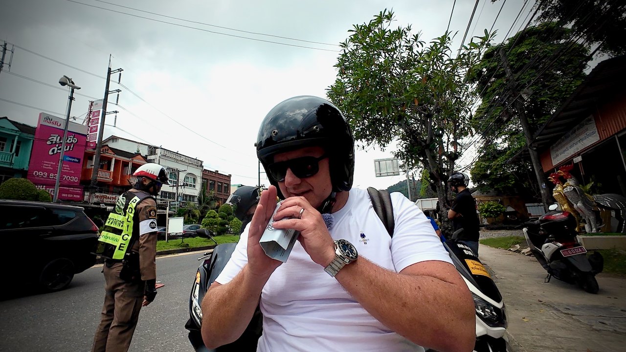 A man wearing a black helmet and sunglasses, saluting the police officers. There is other motorcycles in the background.