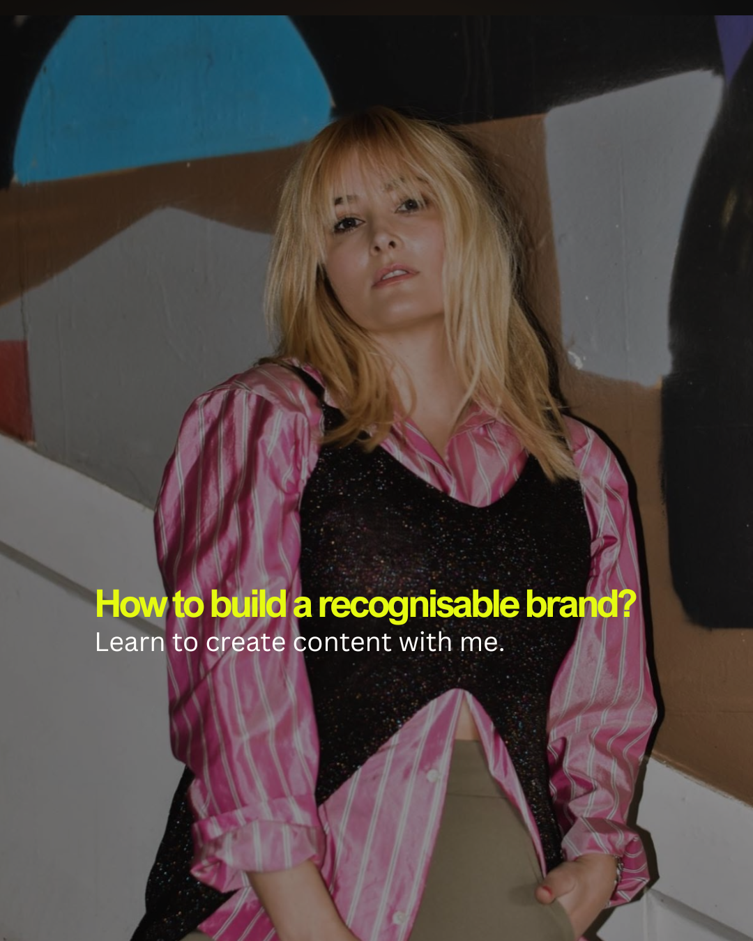 Image of a woman with blonde hair leaning against a colorful abstract mural, wearing a pink striped shirt and black top. Overlaid text reads 'How to build a recognisable brand? Learn to create content with me.'