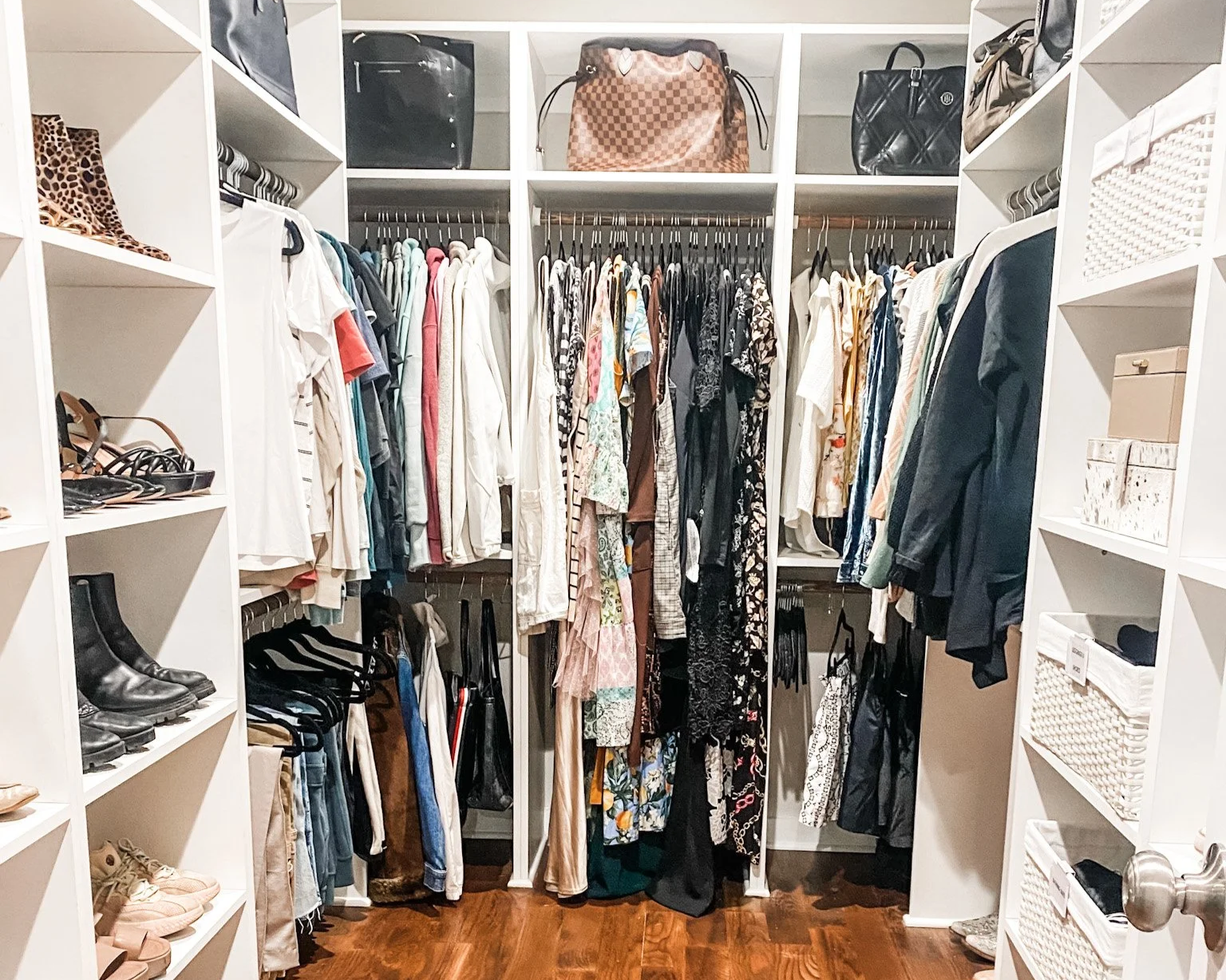 White built-in walk-in closet organization system with shoe shelves, hanging rods, and storage baskets