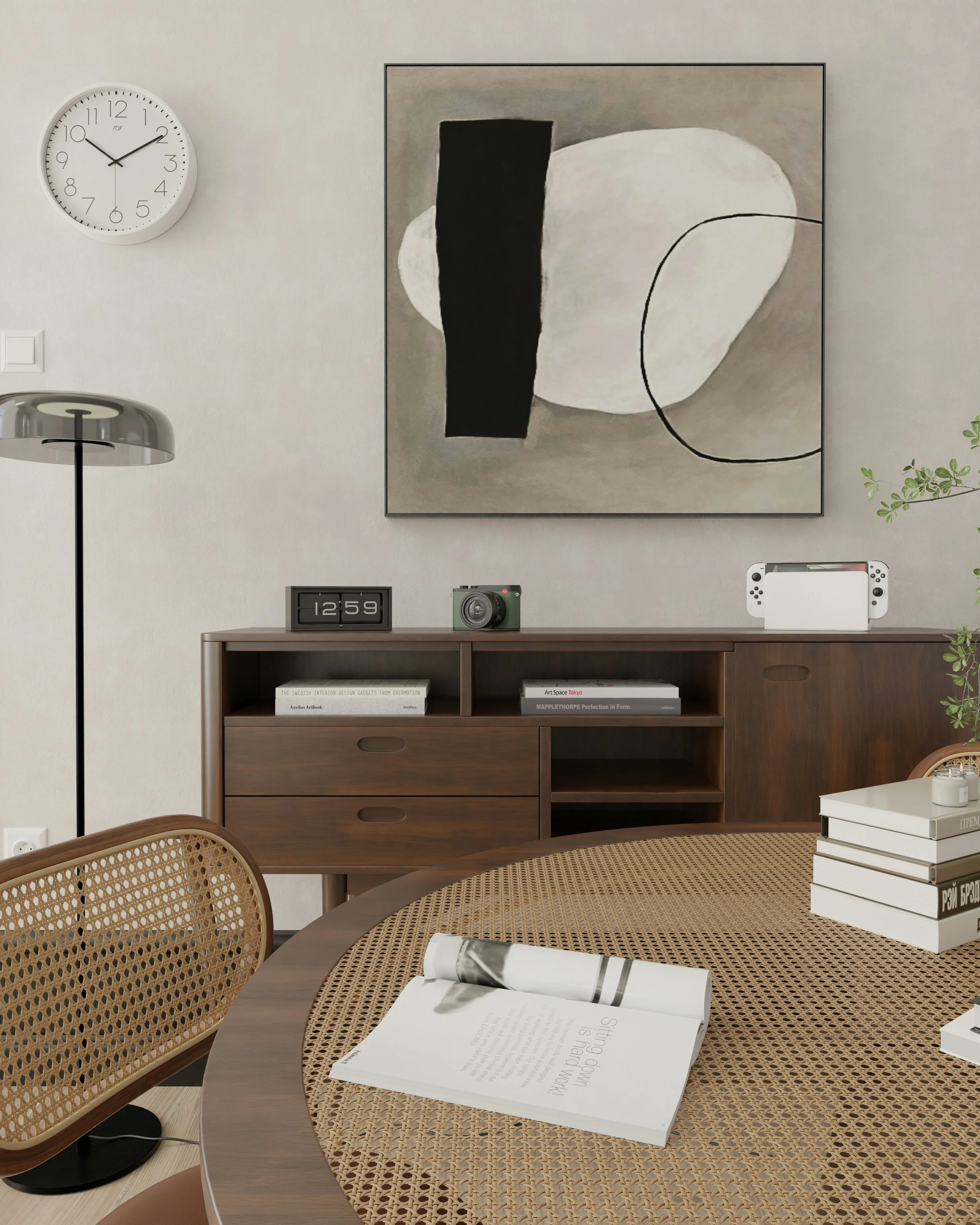 A modern interior room with a round wooden dining table with woven cane pattern top, surrounded by matching cane back chairs. On the table, there is an open magazine. In the background, a wooden sideboard holds a digital clock, camera, and Nintendo Switch. Above, a large abstract black, white, and gray painting hangs on a light-colored wall. To the left, a white wall clock shows the time as 10:11. To the left of the image, a floor lamp with a metallic shade is visible.