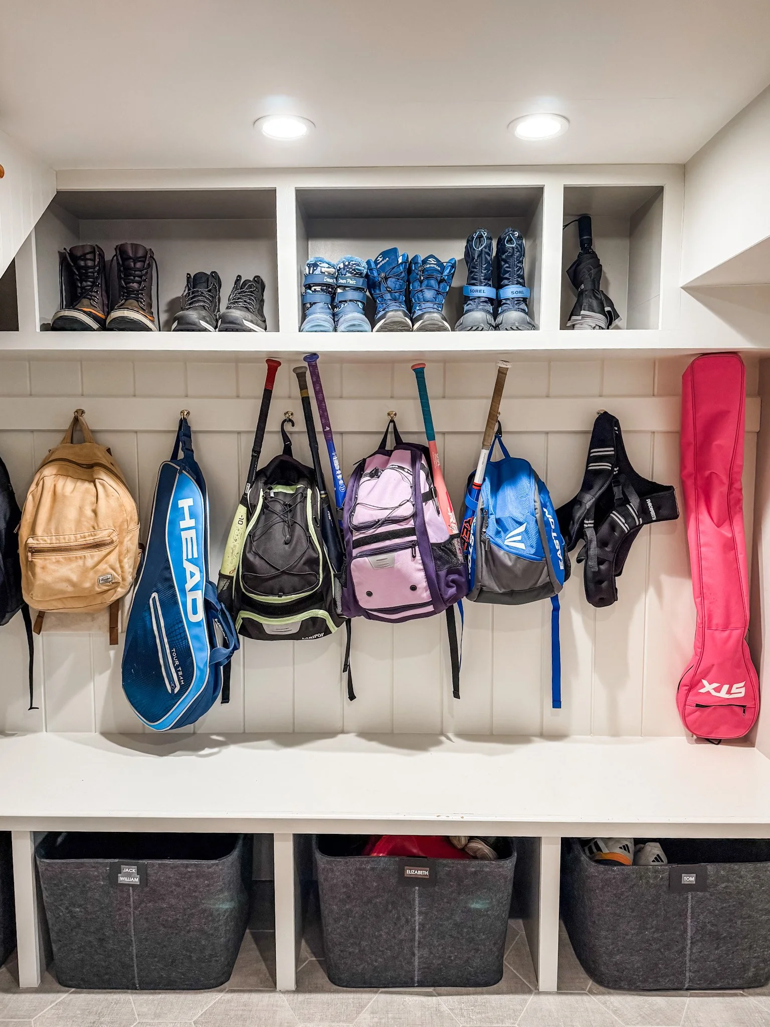 Entryway organization uses wall hooks for backpacks and gear with baskets below for easy-access storage.