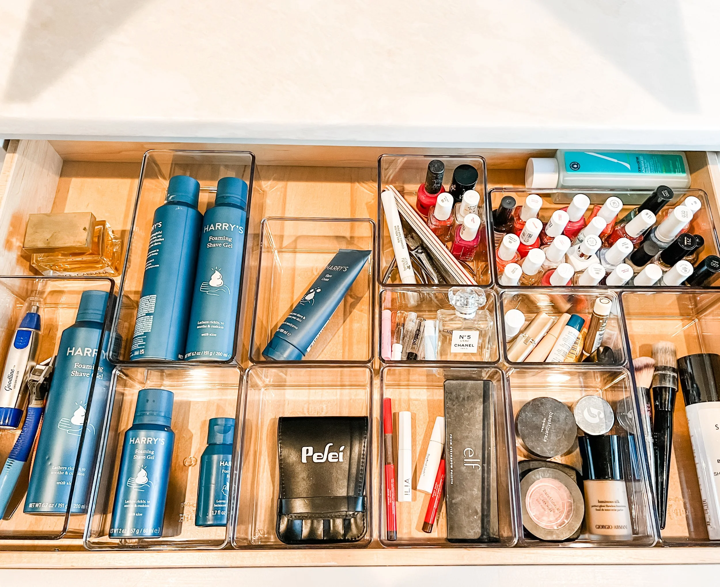 Clear acrylic bins sort makeup and toiletries in a drawer, highlighting home organizing systems.