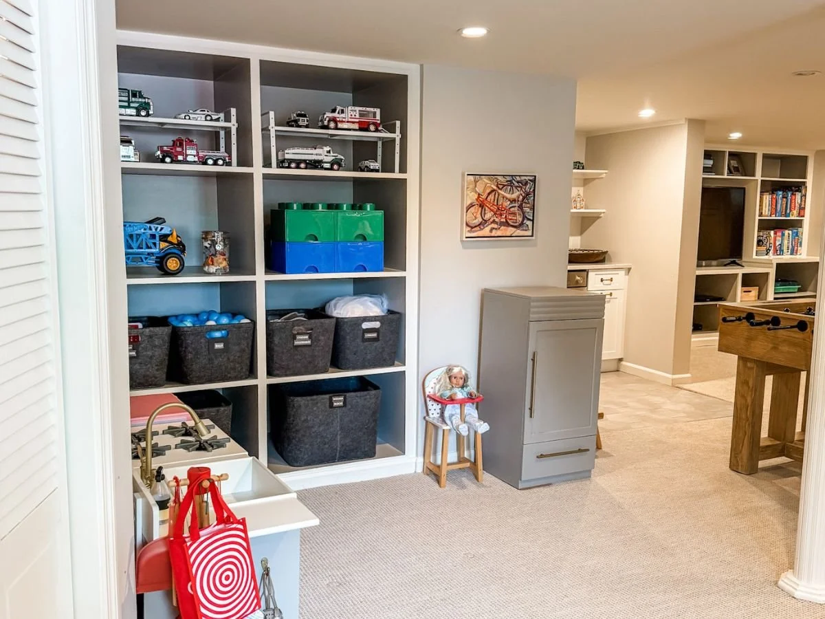 Organized playroom showing how to unpack and organize after moving with labeled bins and toy storage.