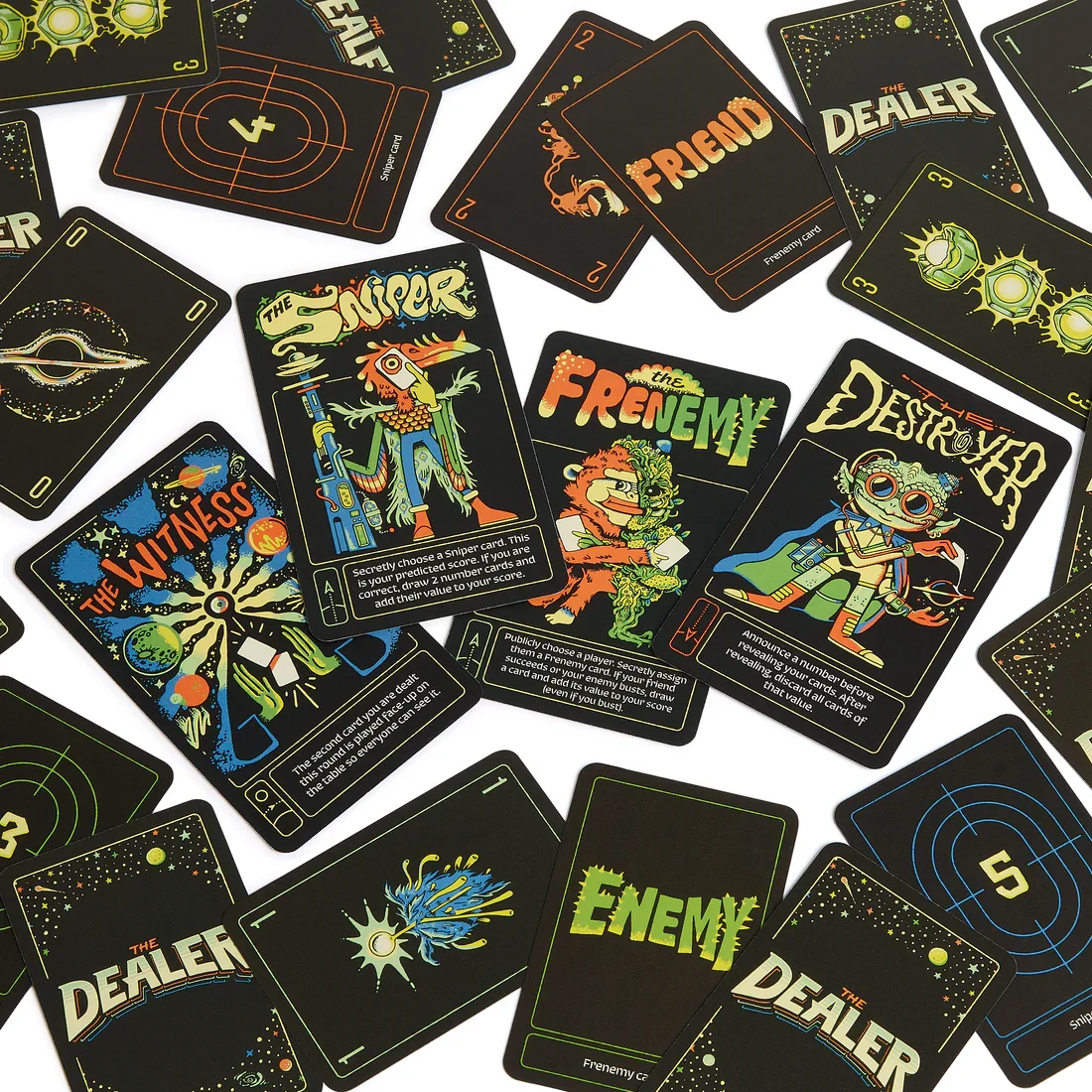 Set of colorful sci-fi themed playing cards scattered on a white surface. The cards feature characters like Sniper, the Frenemy, the Destroyer, and the Dealer, with illustrations of alien and space themes. The game 'The Dealer'