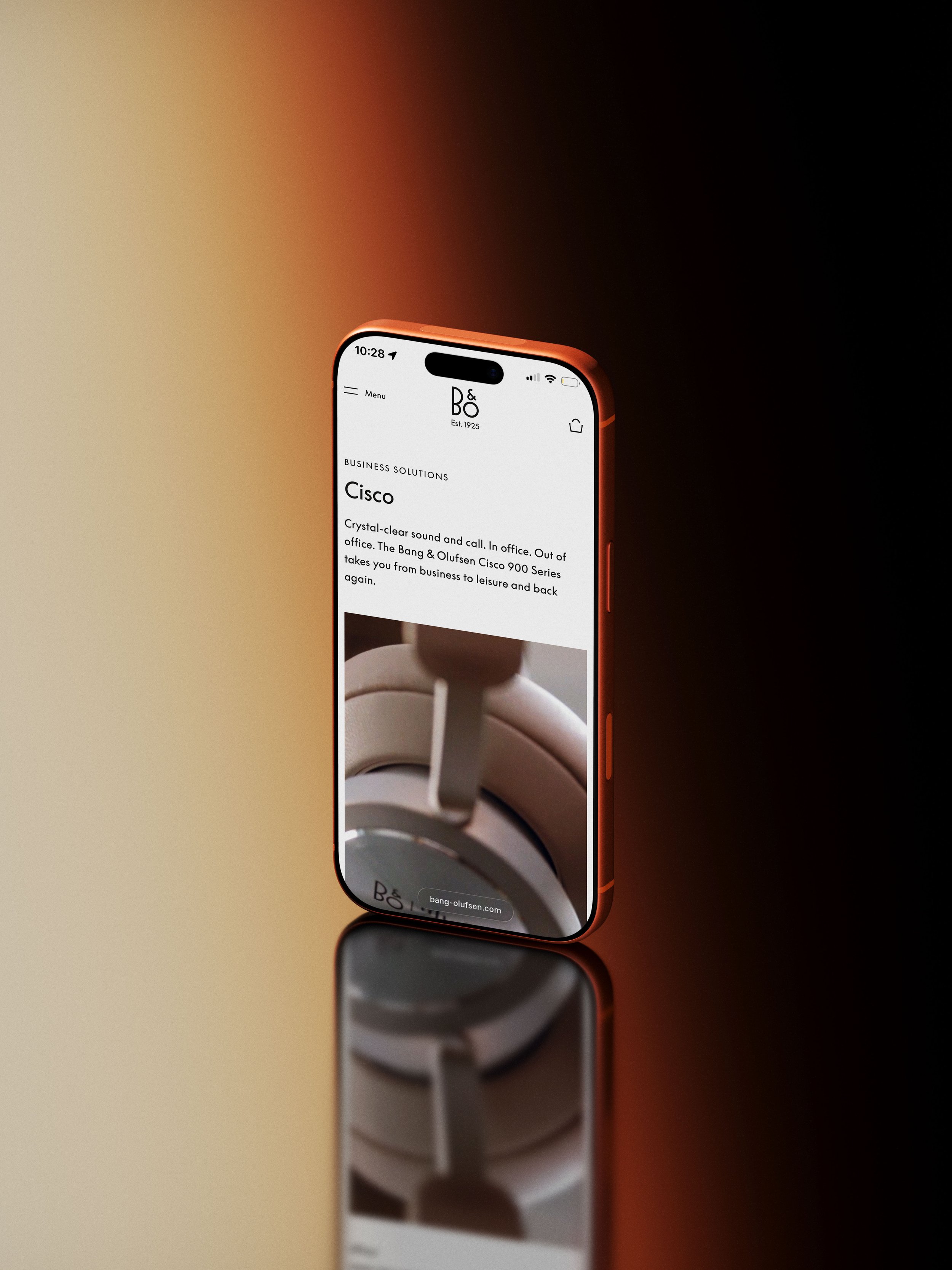 Product still life by ST Davis for Bang & Olufsen x Cisco — smartphone displaying the B&O Cisco headphones on a reflective surface with warm gradient lighting