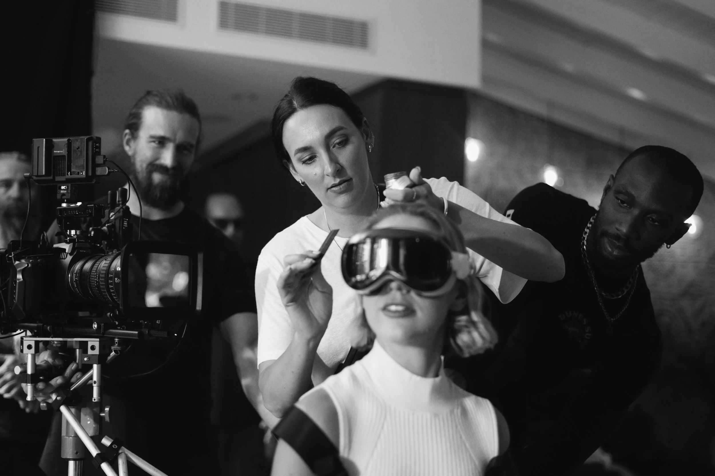 Behind the scenes on a video production directed by ST Davis — wardrobe and styling prep with talent and crew on set, black and white production still