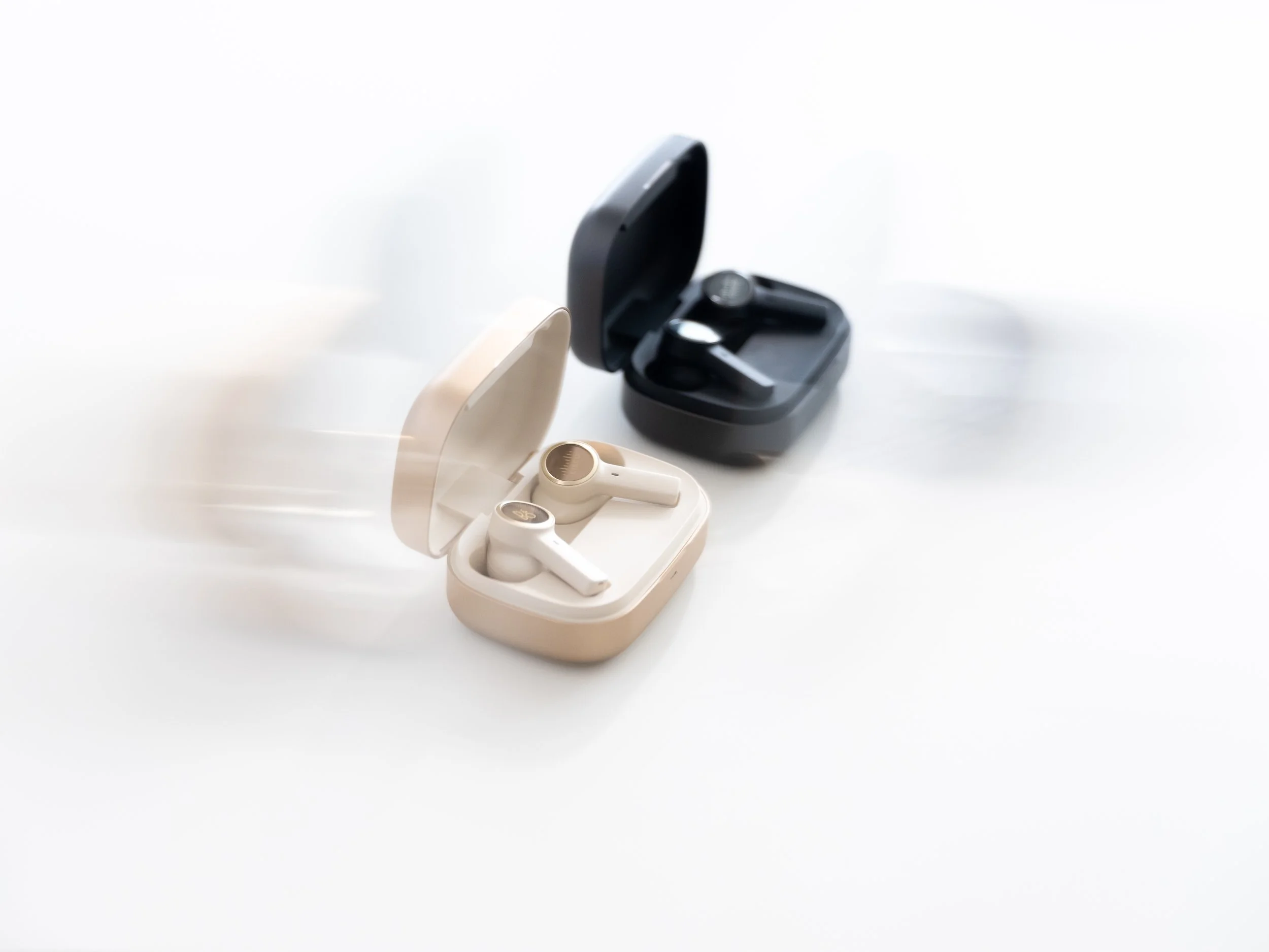 Product photography by ST Davis for Bang & Olufsen x Cisco — wireless earbuds in beige and black colorways with open charging cases on a clean white surface
