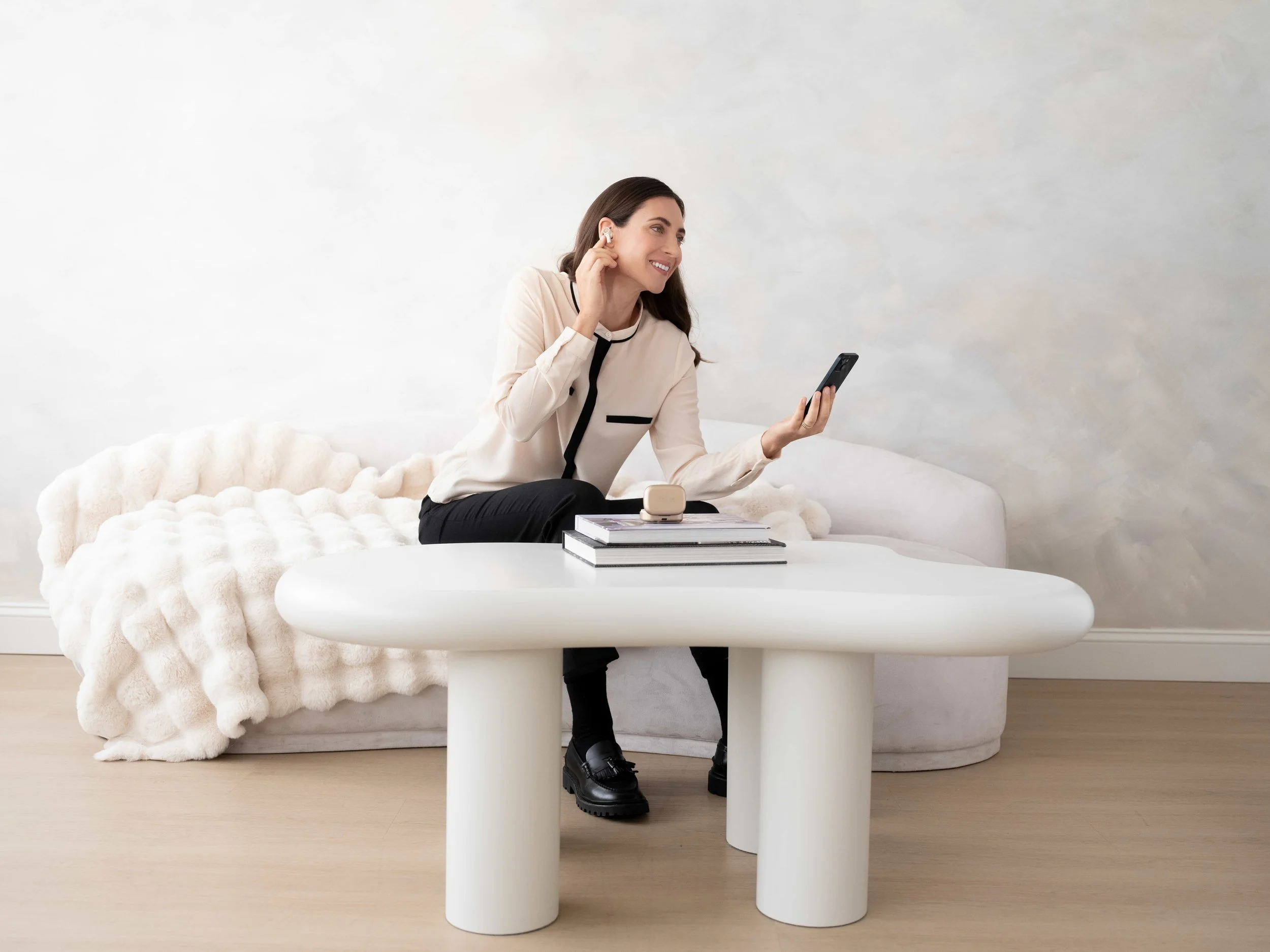 Commercial lifestyle photography by ST Davis for Bang & Olufsen x Cisco — woman using earbuds with smartphone in a minimal contemporary interior