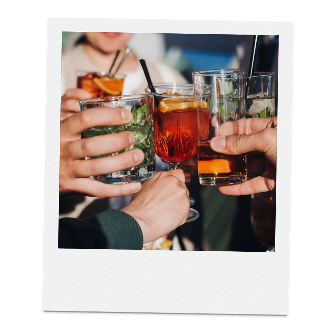 Multiple people clinking glasses with cocktails and drinks at a social gathering.