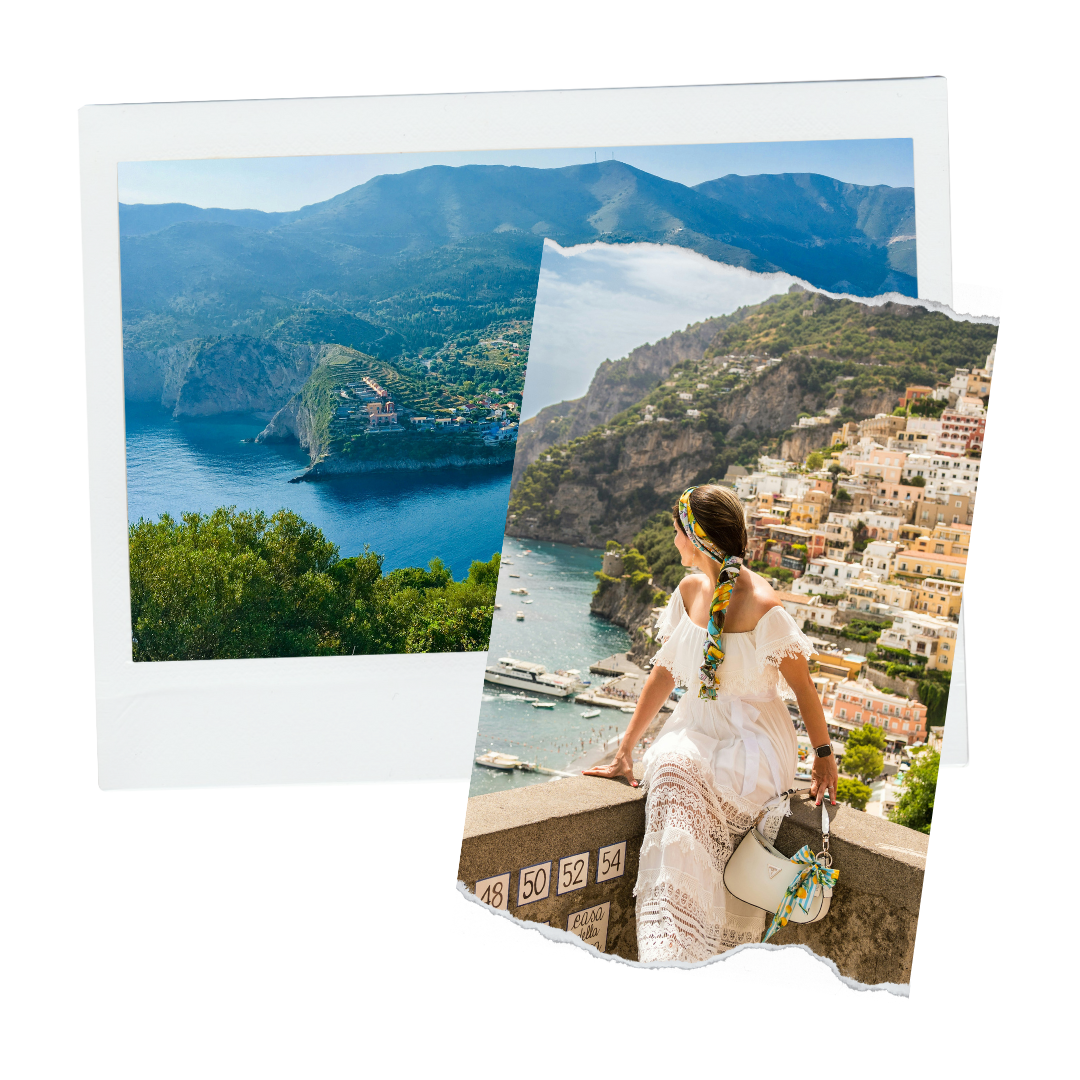 A woman sitting on a ledge overlooking a coastal town with colorful buildings, mountains, and boats in the water.