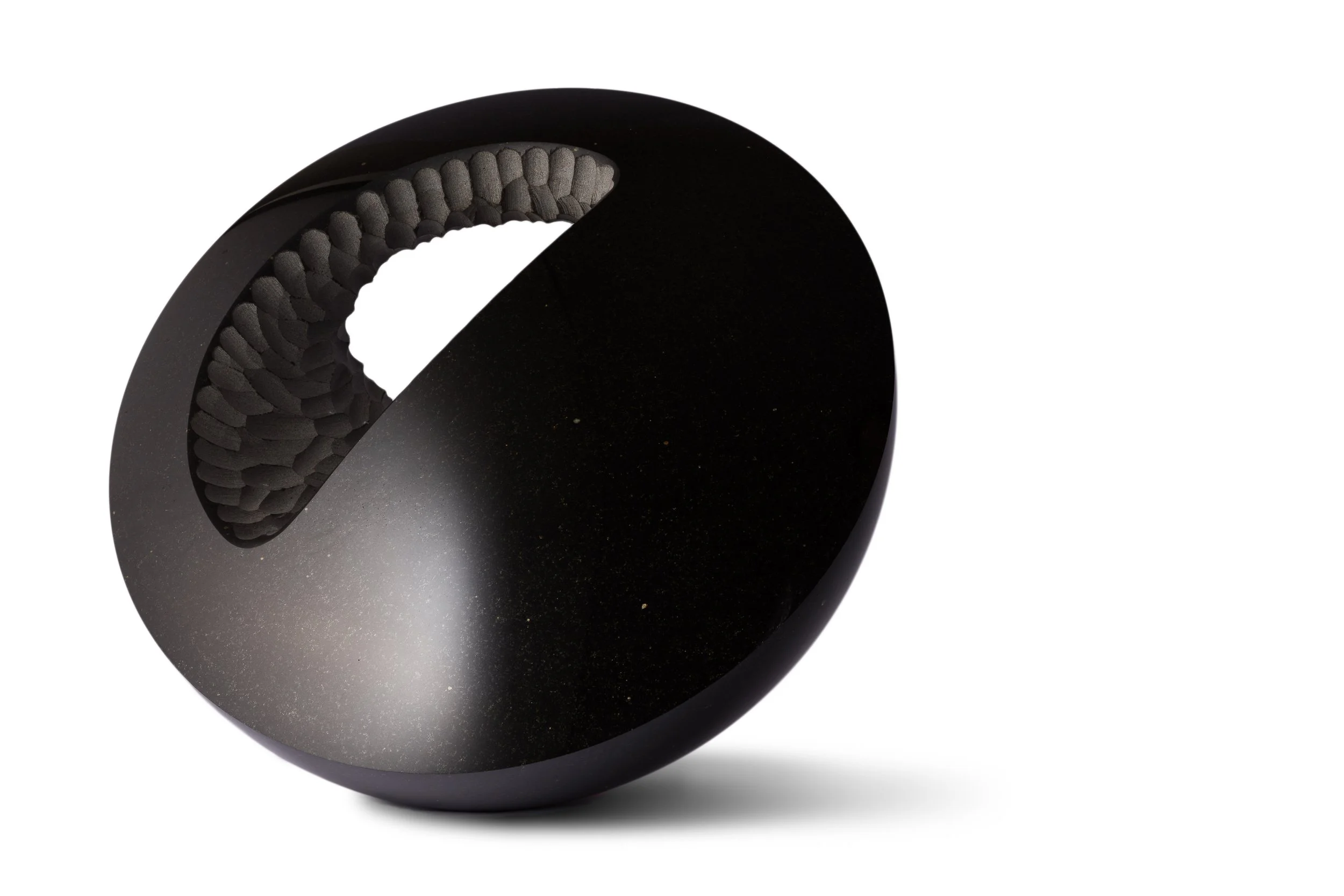 Close-up of a black basalt sculpture with a textured, patterned surface.