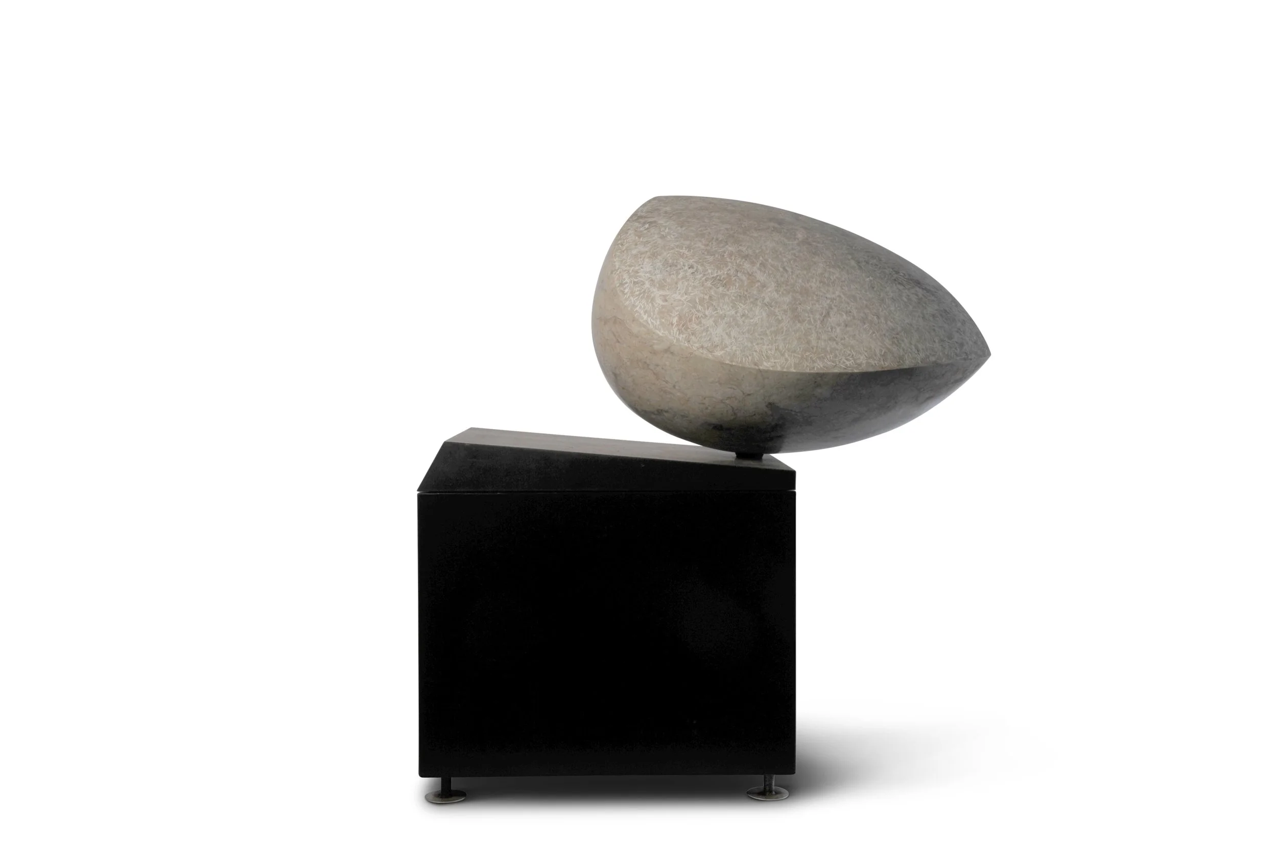 A modern sculpture of a smooth, oval-shaped stone resting on a black rectangular pedestal.