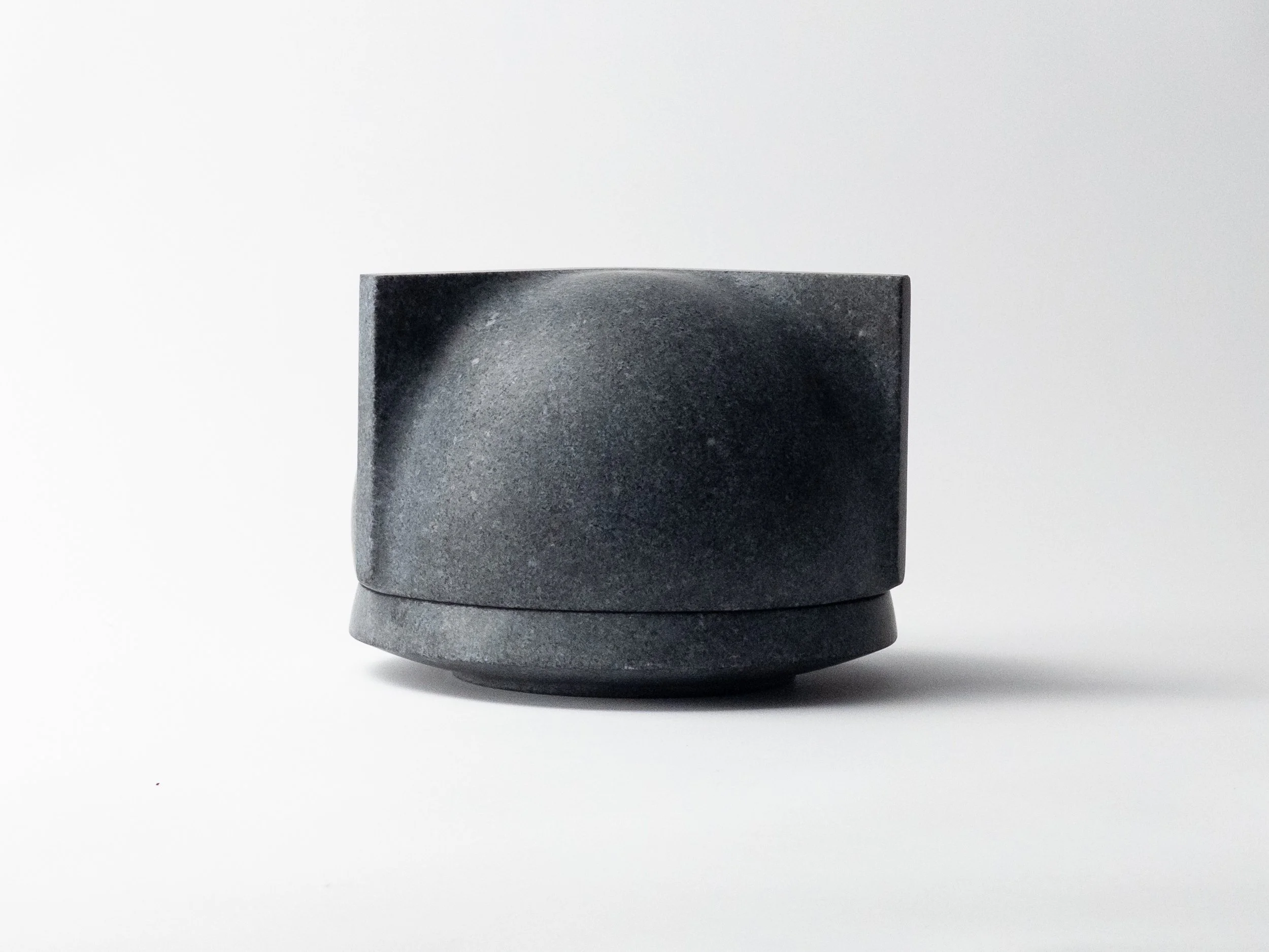 A black stone cup with a smooth surface sits on a white background.