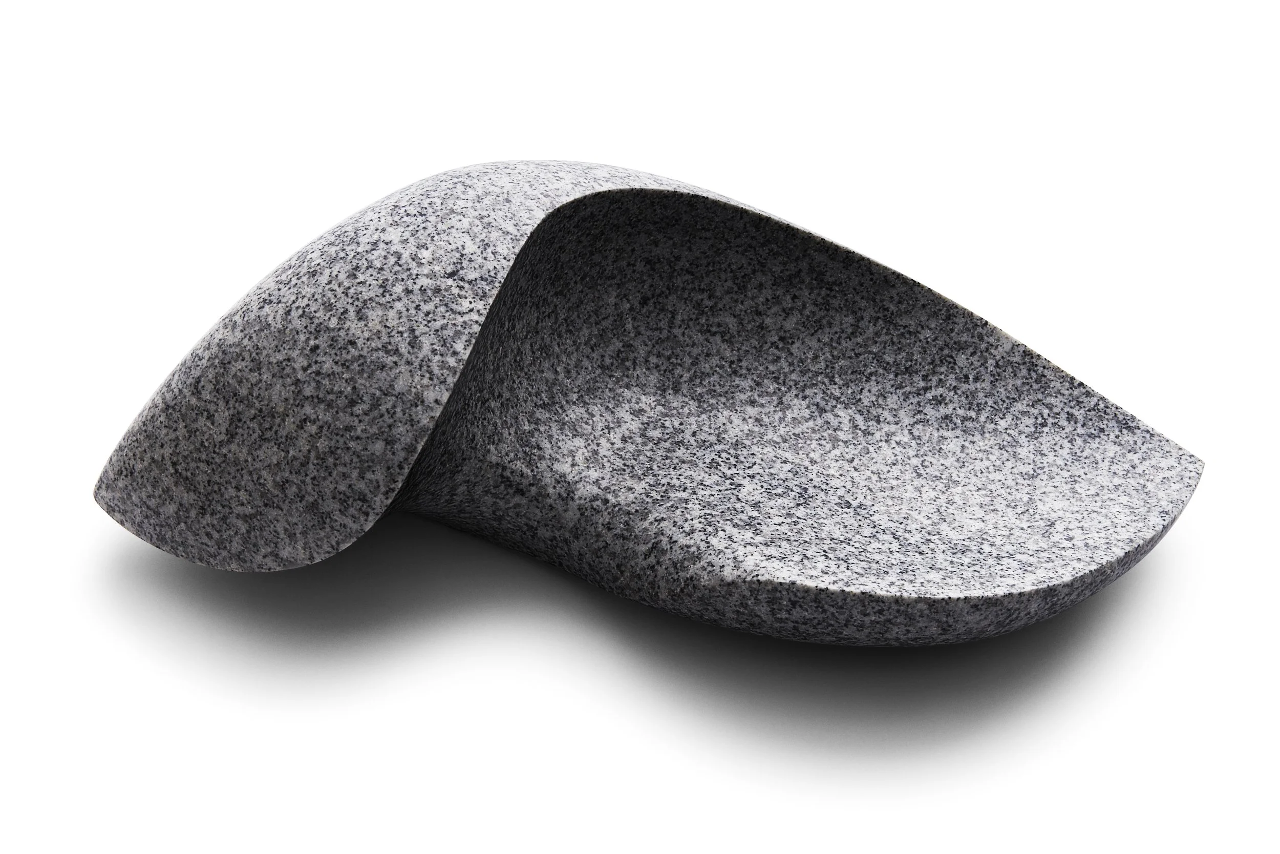 Close-up of a smooth, polished, gray granite stone with a speckled pattern, resting on a white surface.