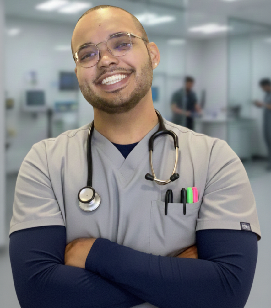 Smiling male healthcare professional wearing scrubs and stethoscope in a hospital setting.