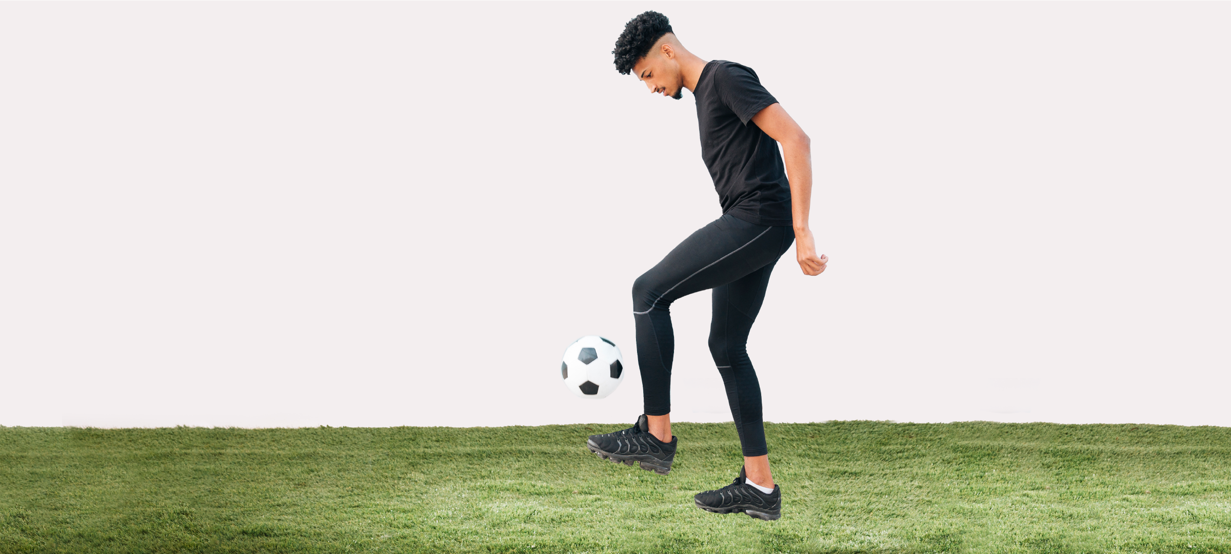 adult male player kicking a ball on an indoor turf field