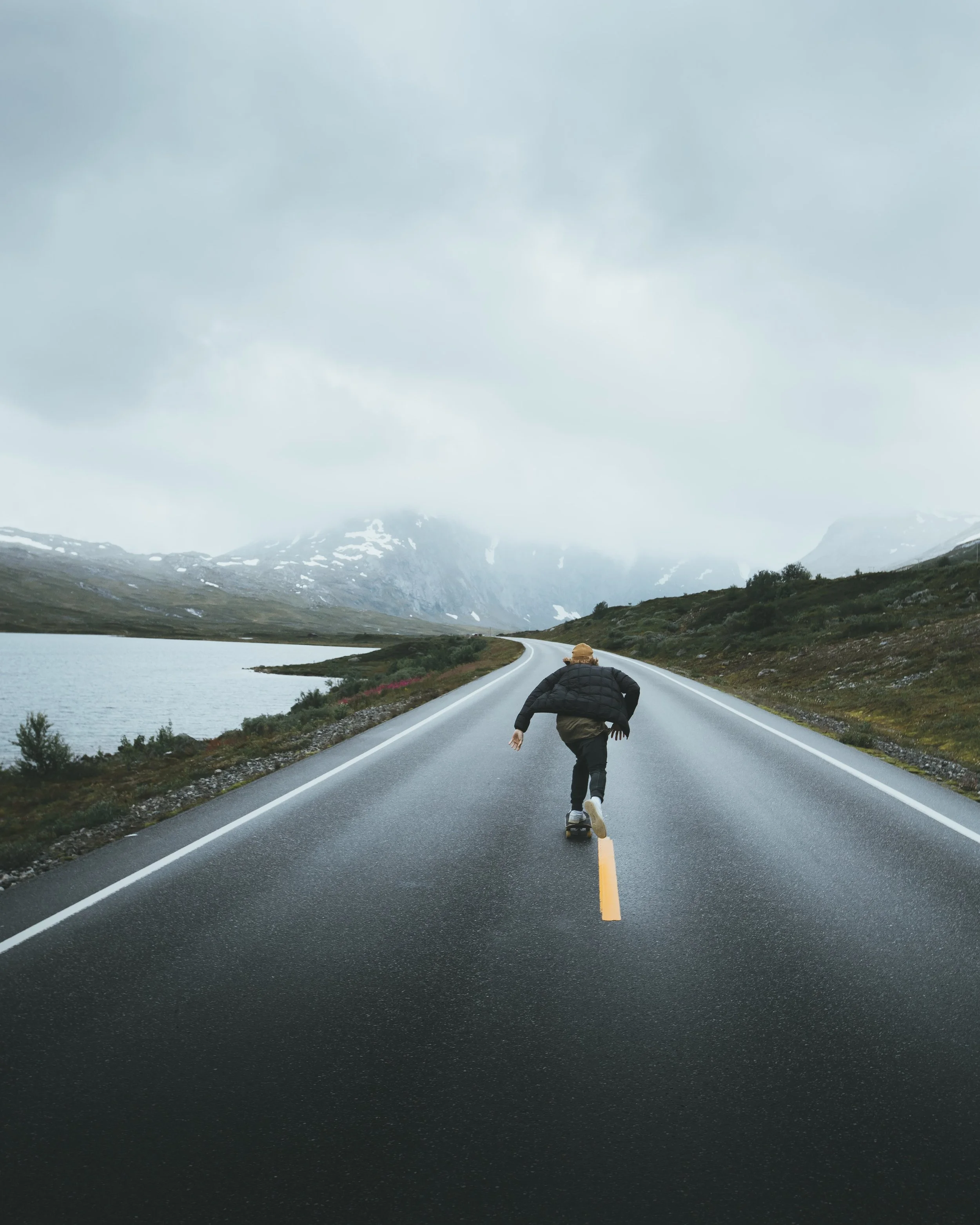 A woman skateboarding on a road in a foggy cold weather
