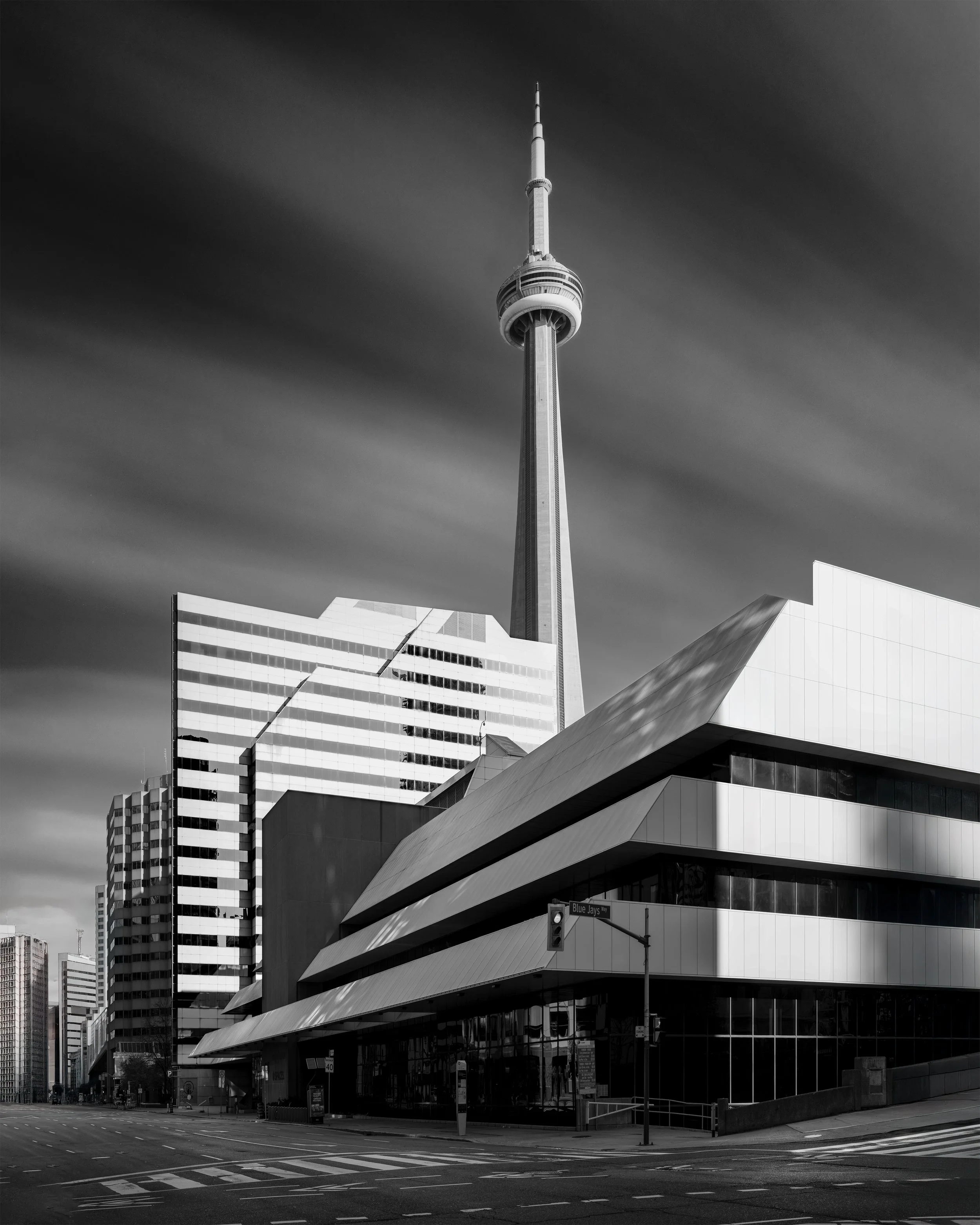 Black and white photo of Toronto skyline with CN Tower and modern buildings on a cloudy day.