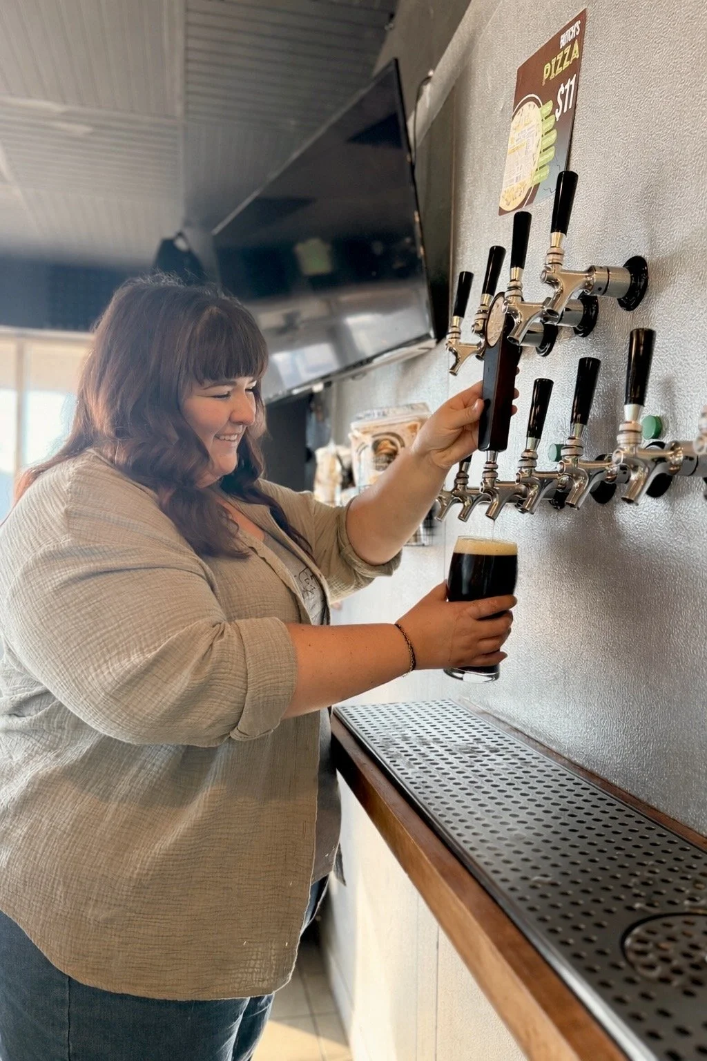 woman pouring a dark porter at a craft beer brewery in Peoria, IL