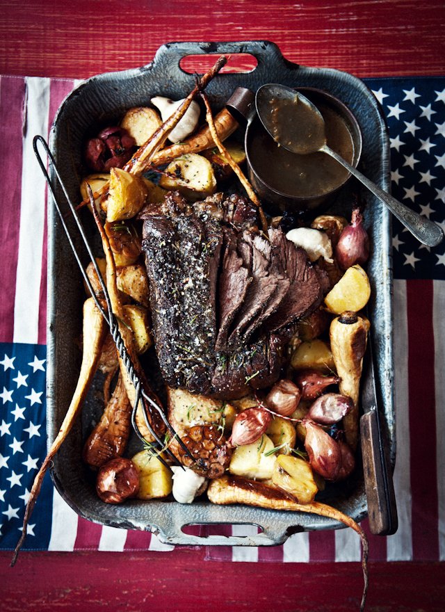 Roast beef dinner with roasted potatoes, carrots, and onions, served with gravy.
