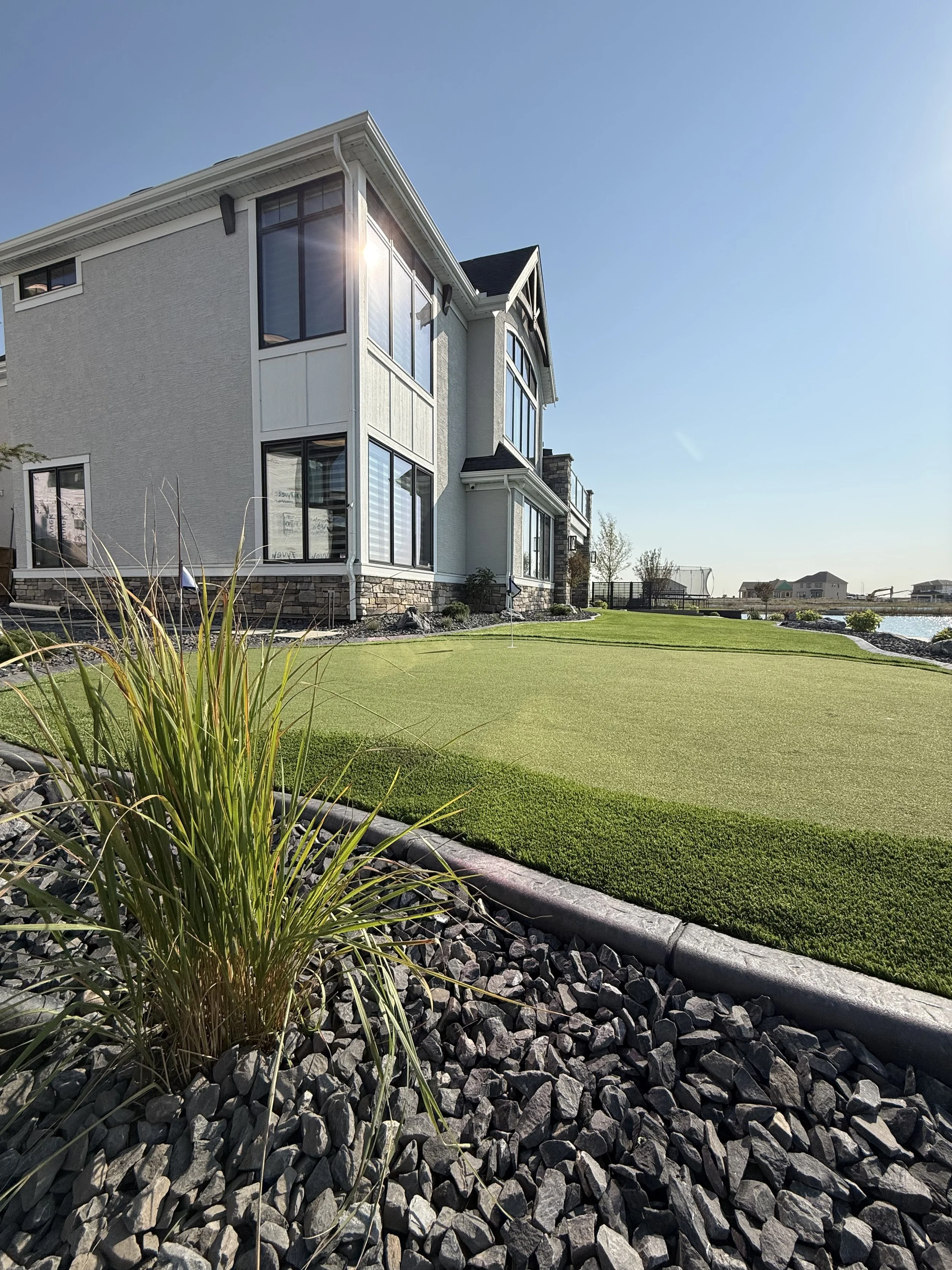 A picture of a clean house with stucco, clean windows, clean artificial turf, putting green, in Calgary.