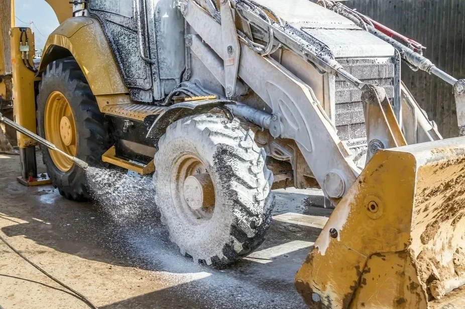 A large yellow construction vehicle washing off with water spray.