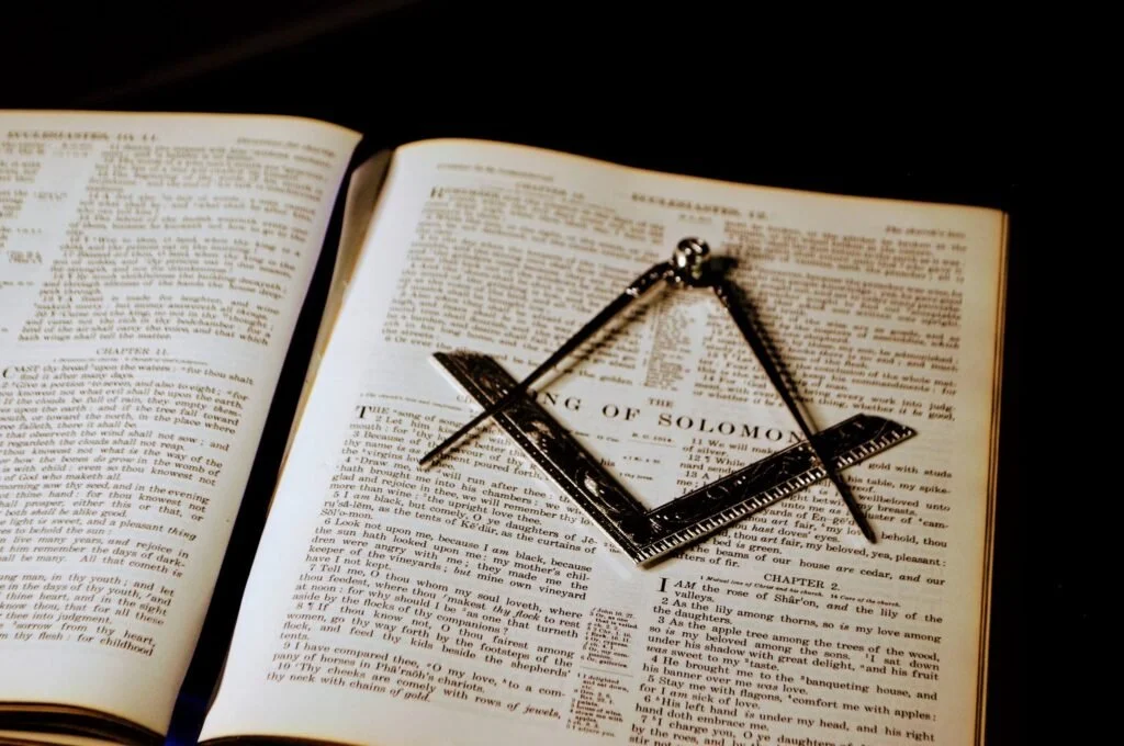 Open Bible with a metal square on a black background.