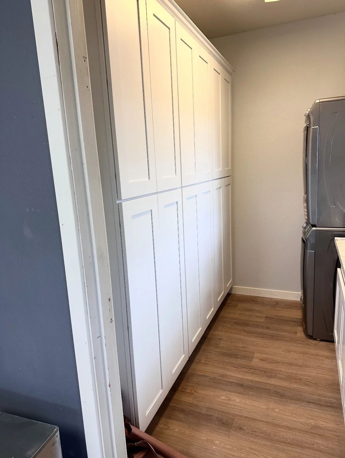 A laundry room with white cabinets, a washer and dryer, and wood flooring.