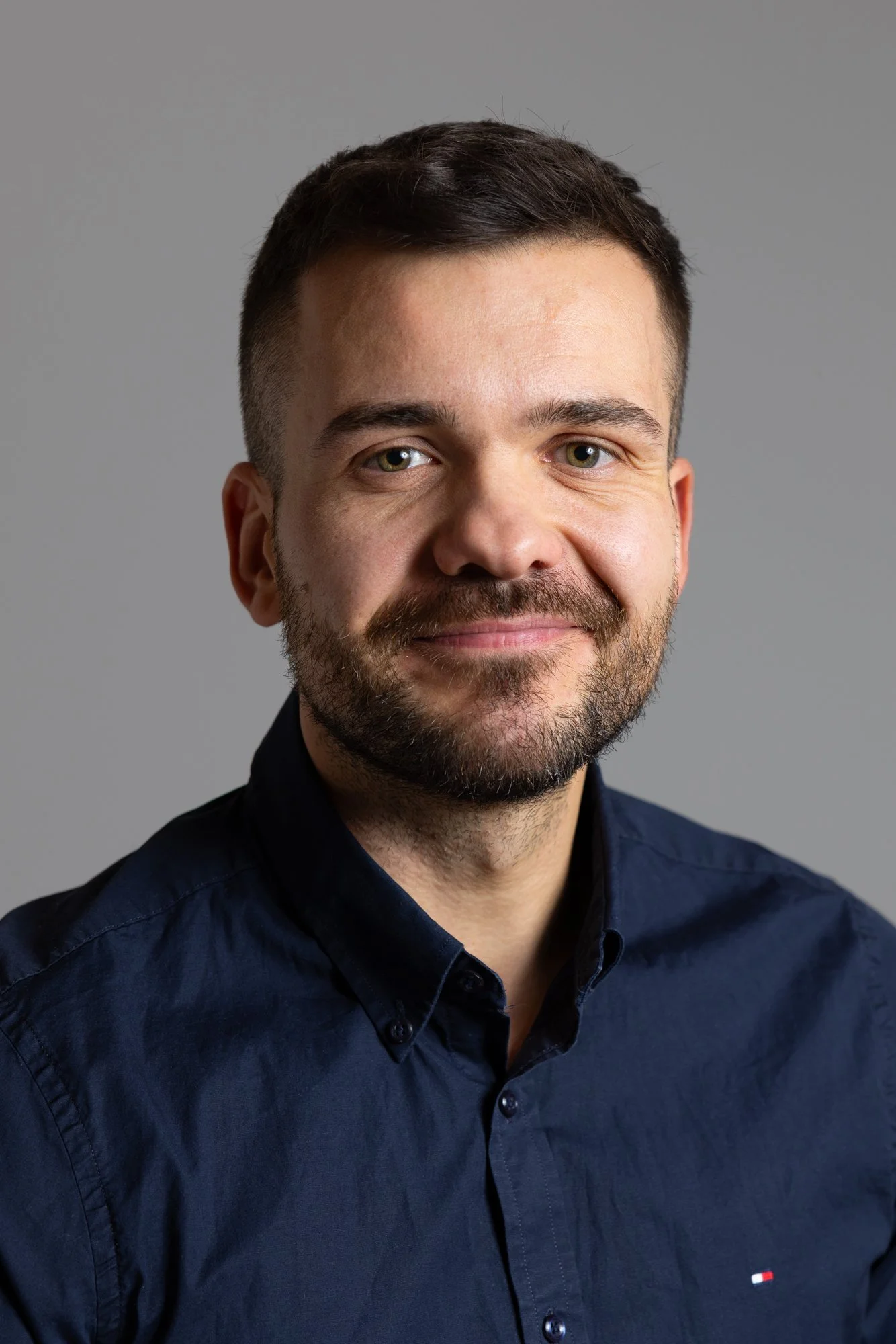 Porträt eines lächelnden Mannes mit dunklem Hemd auf grauem Hintergrund. Porträt, Businessporträt